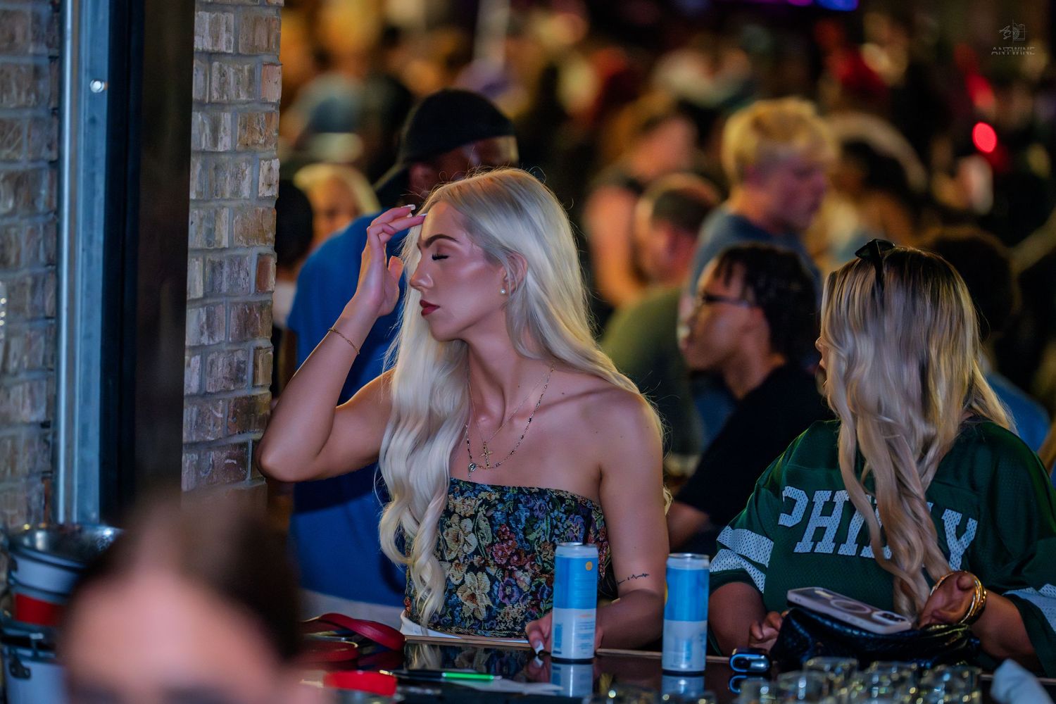 Blonde woman in a strapless top at a crowded nightclub bar.