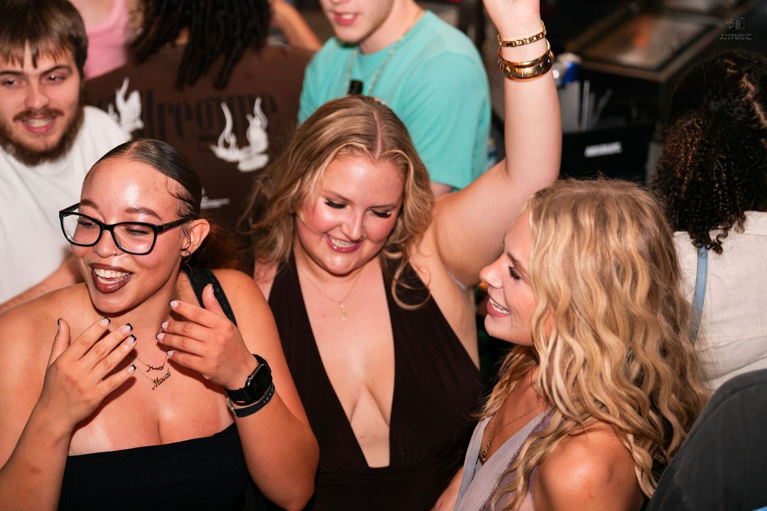 Three women laughing and having fun together at a lively nightclub or bar event.