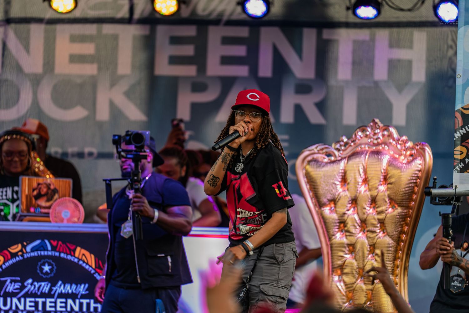 Performer singing on stage at the 6th Annual Juneteenth Block Party, wearing a red cap and black outfit.