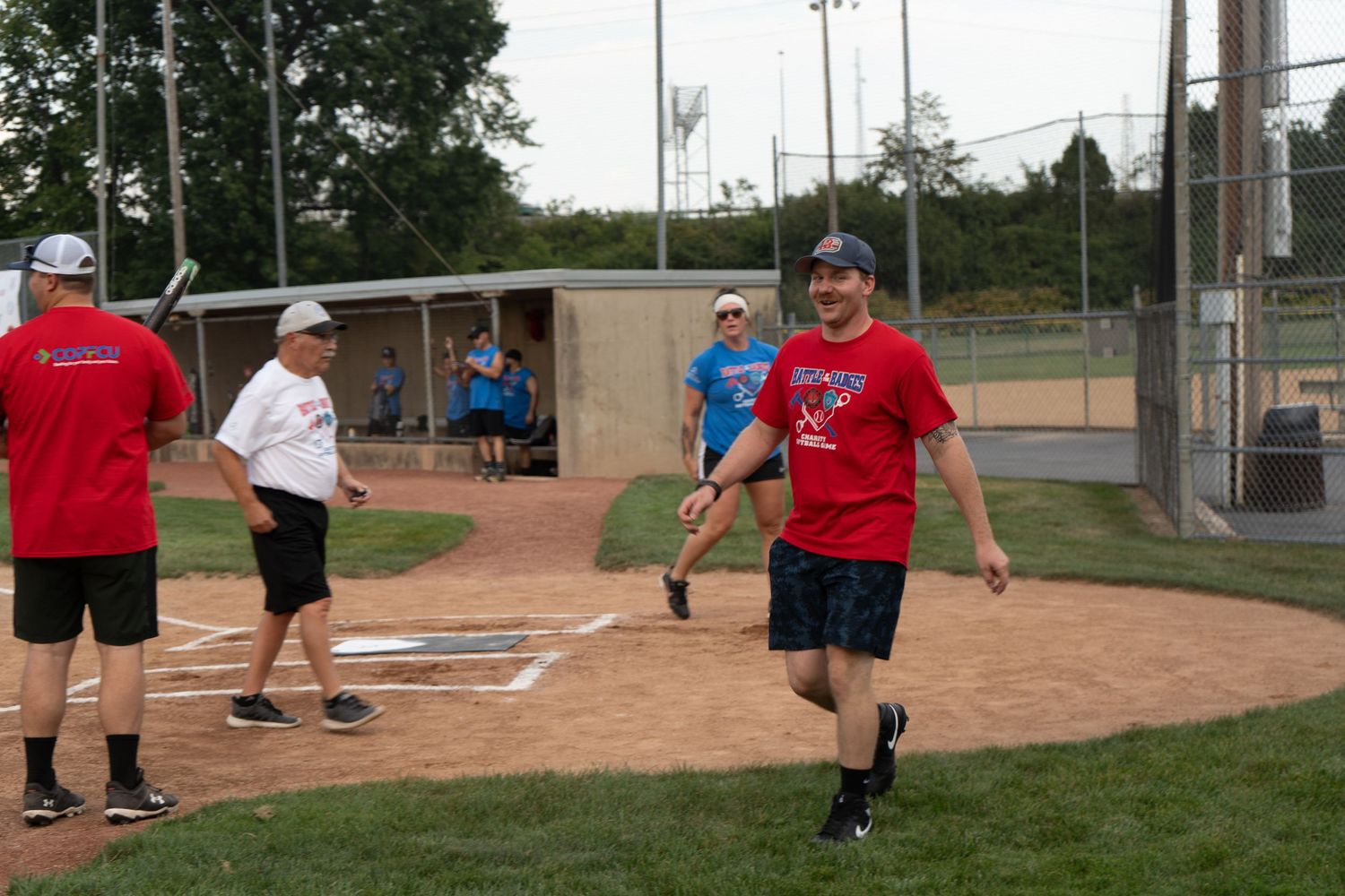 Players gathered on a softball field during a casual recreational game on a warm sunny day.