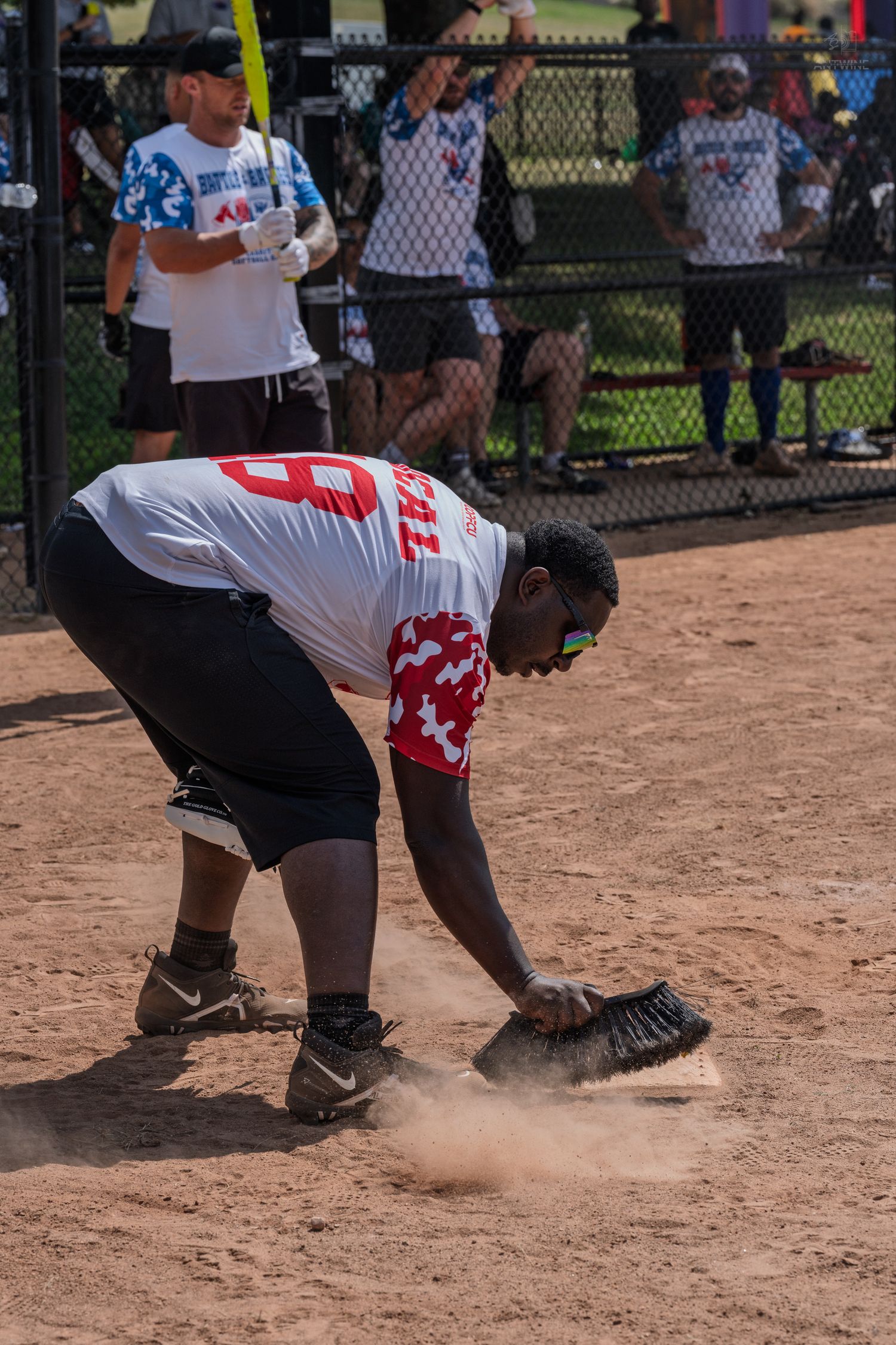 Softball player fielding a ground ball in the dirt during a charity softball game outdoors.