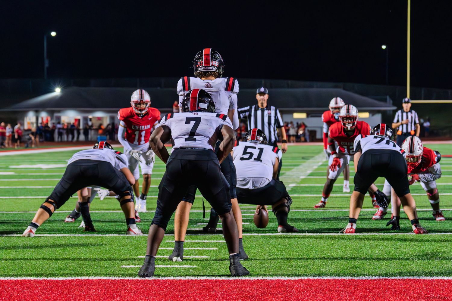 Colerain football team lines up against opponents at the line of scrimmage during a night game.