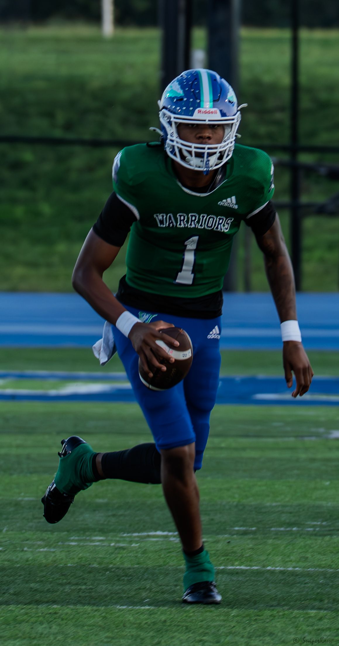 Warriors football player #1 scrambles with the ball during a high school football game.