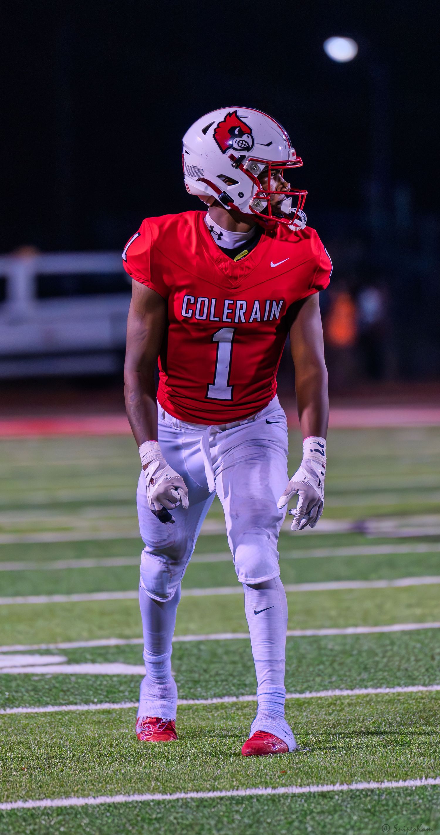 Colerain Cardinals player number 1 stands ready in red uniform and white helmet on turf field.