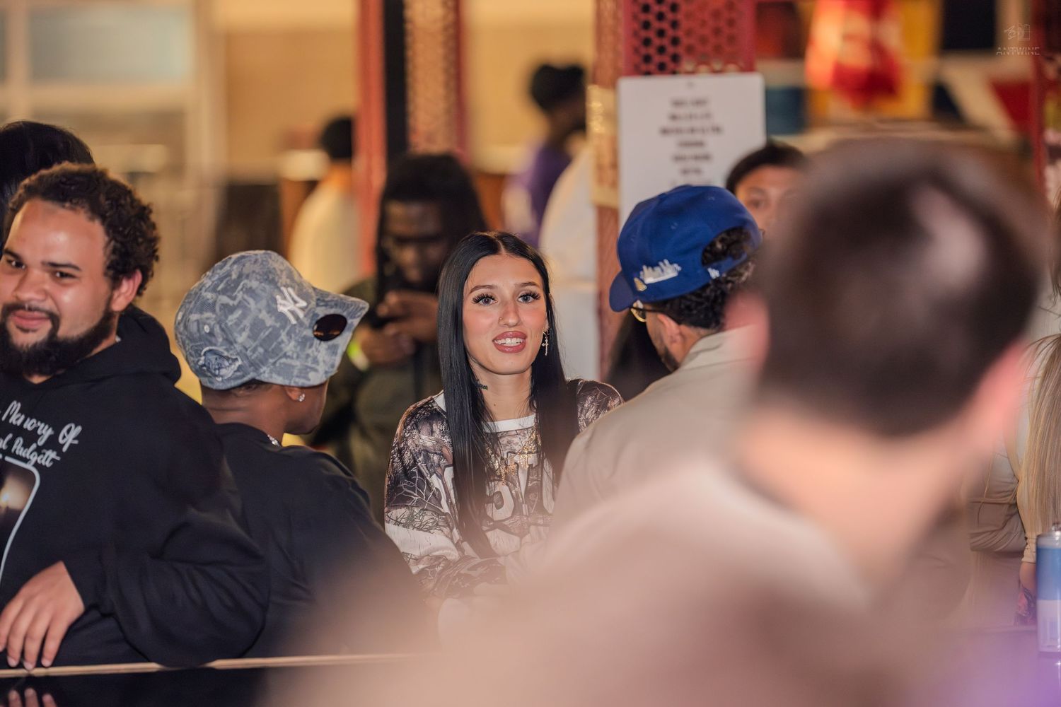 Young woman smiling warmly while socializing in a crowded nightclub setting.