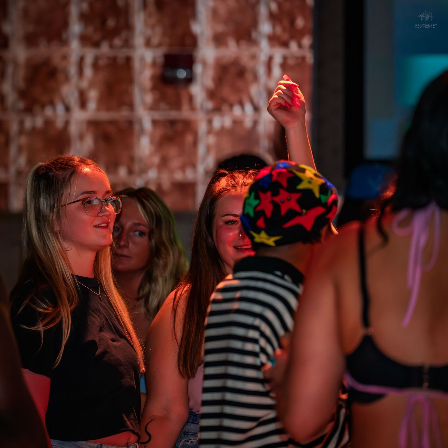 Young women dancing and enjoying themselves at a colorful nightclub party.