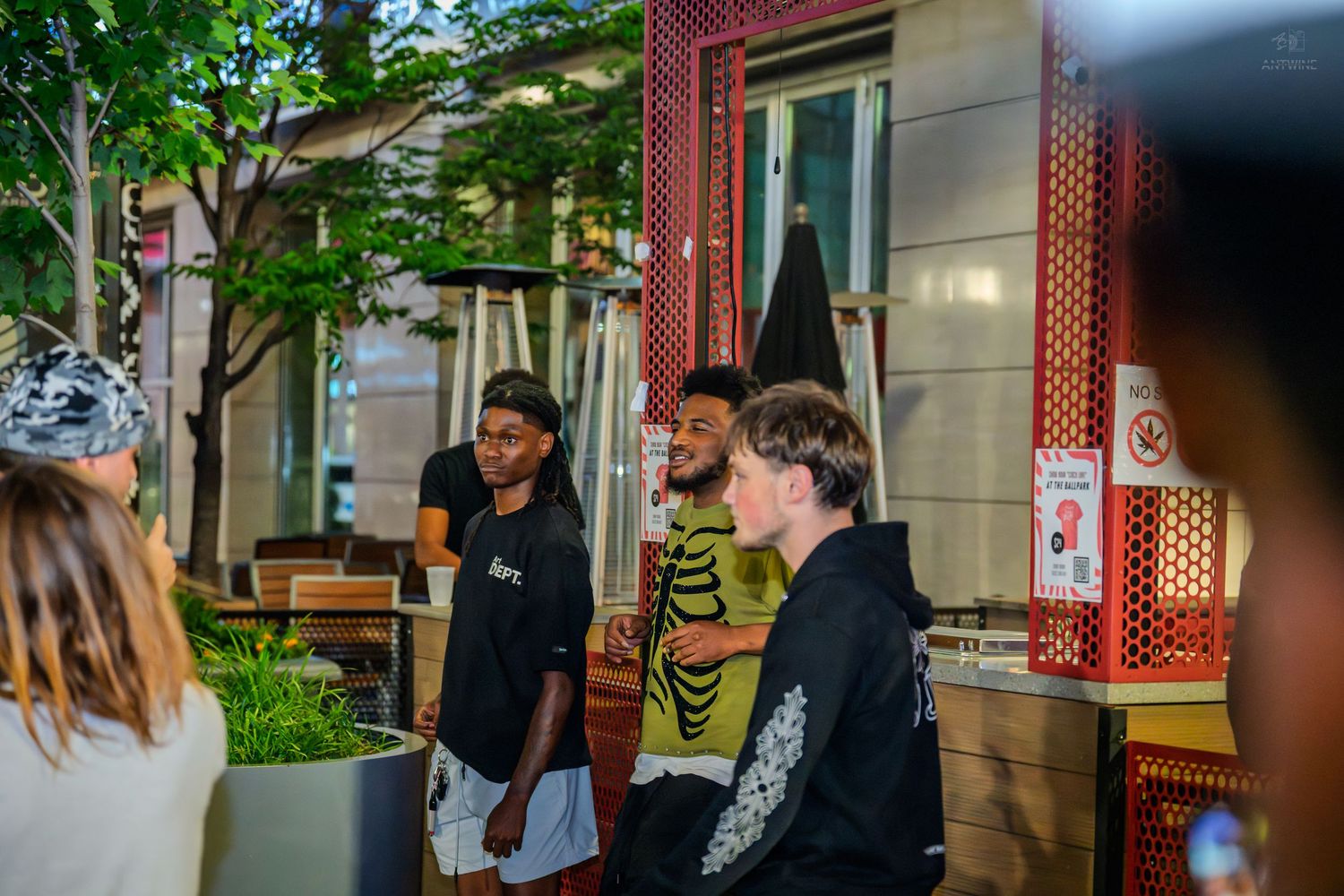 Group of young people socializing outside restaurant at night.