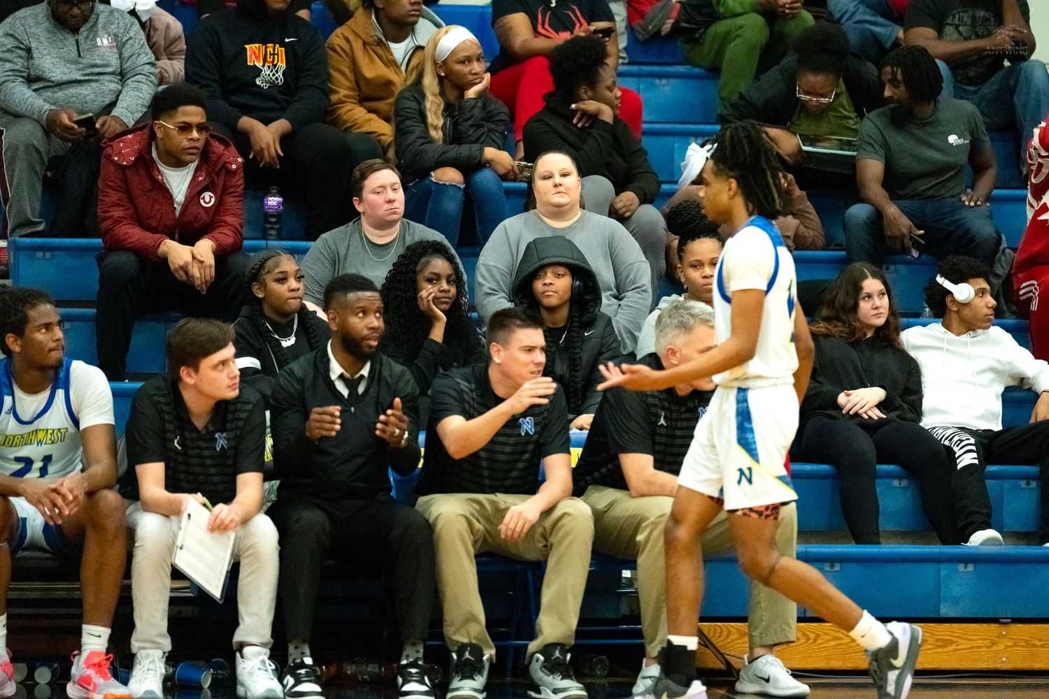 Northwest high school basketball player talks with coaching staff on the sideline during a game.
