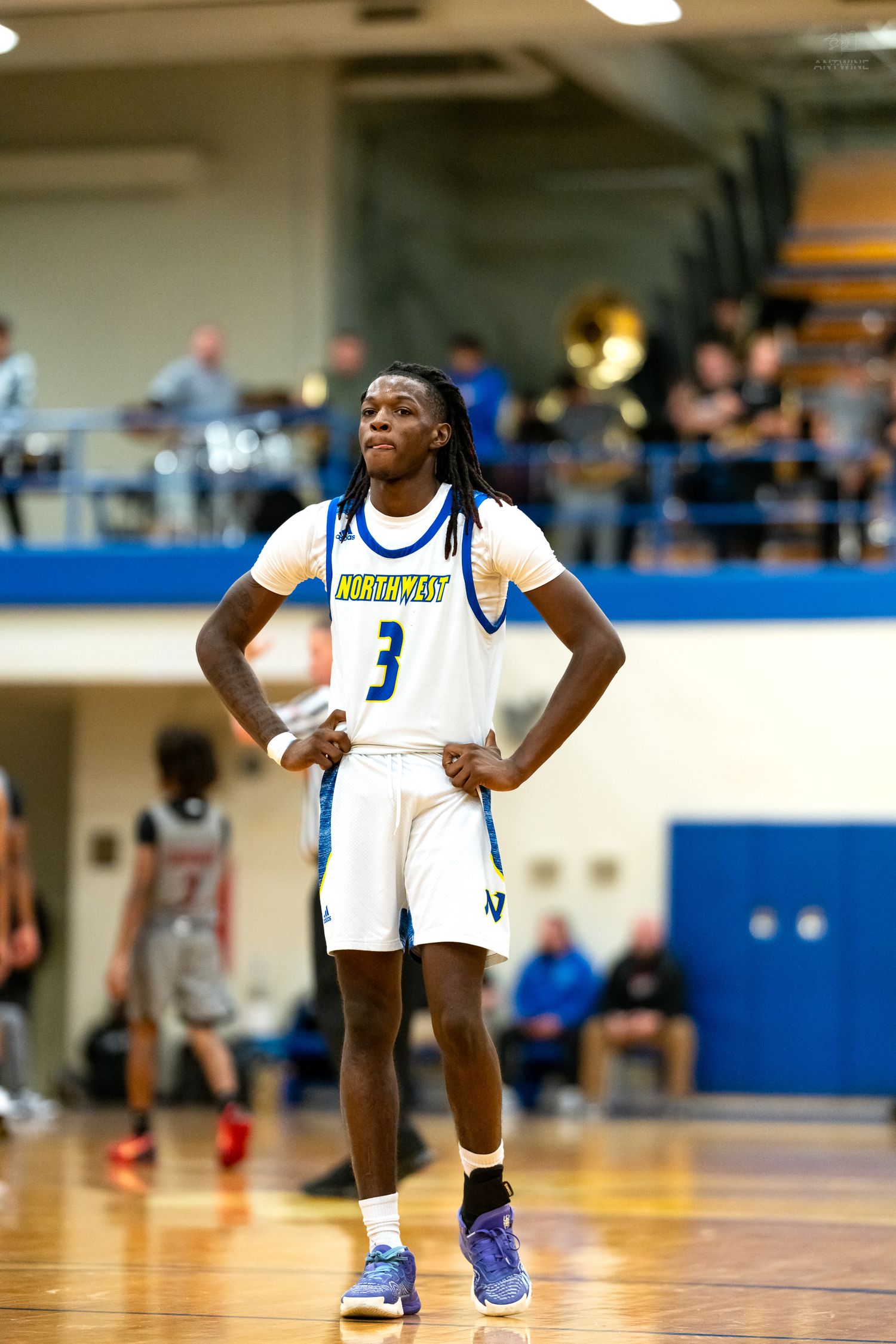 Northwest high school basketball player #3 stands with hands on hips during a game.