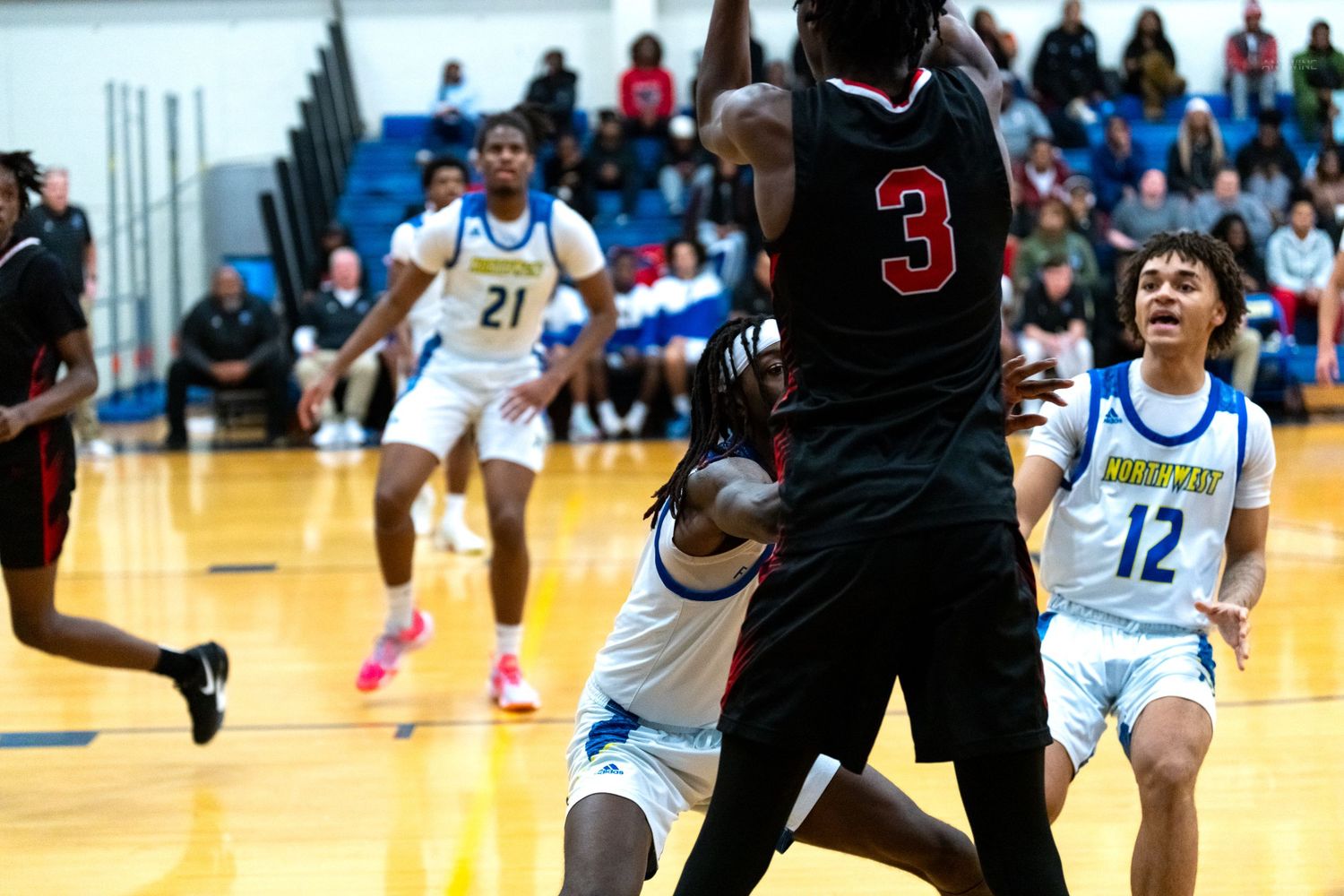 Player wearing number 3 red jersey drives to the basket during a high school basketball game.