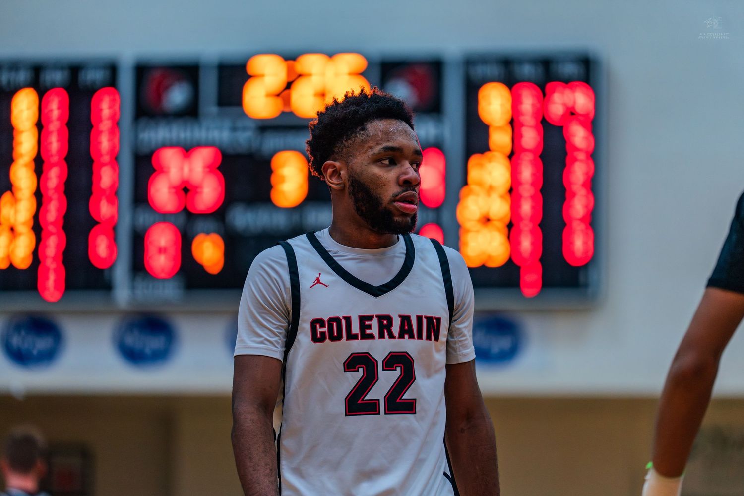 Colerain high school basketball player #22 stands near scoreboard during game.