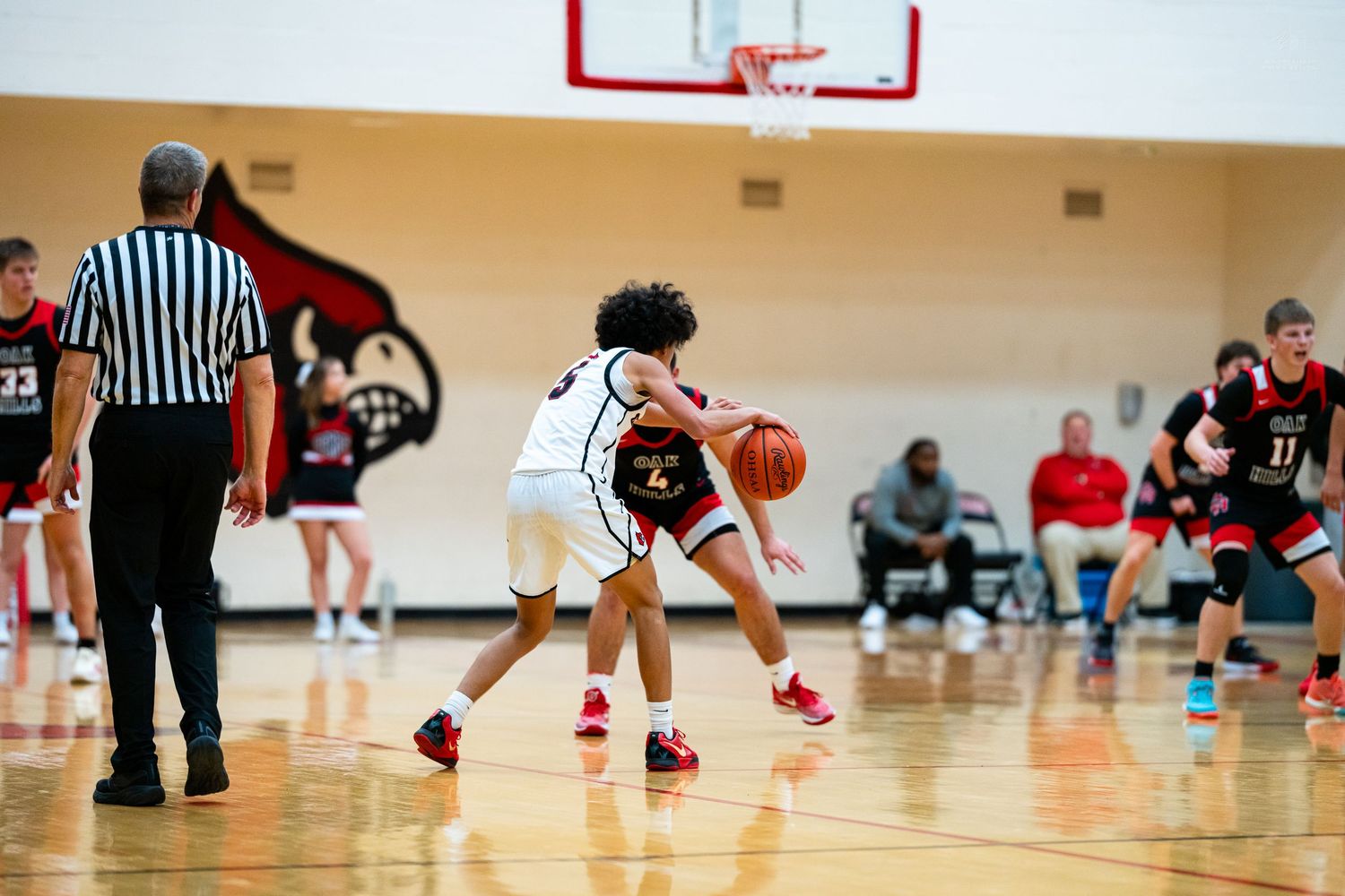 Young basketball player in white uniform dribbles past defender during youth basketball game.