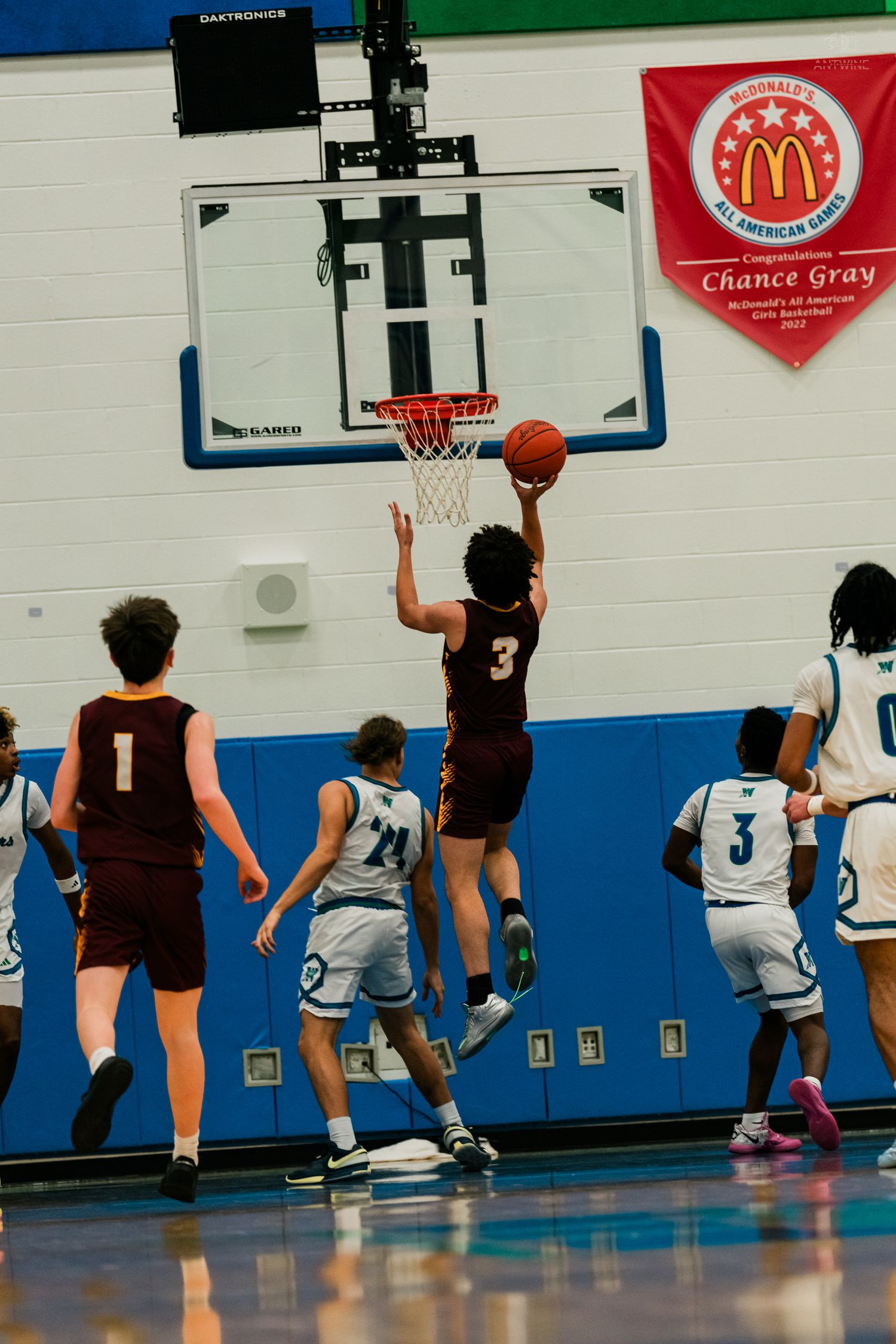 Turpin player #3 attempts a layup over Winton Woods defenders during a high school basketball game.