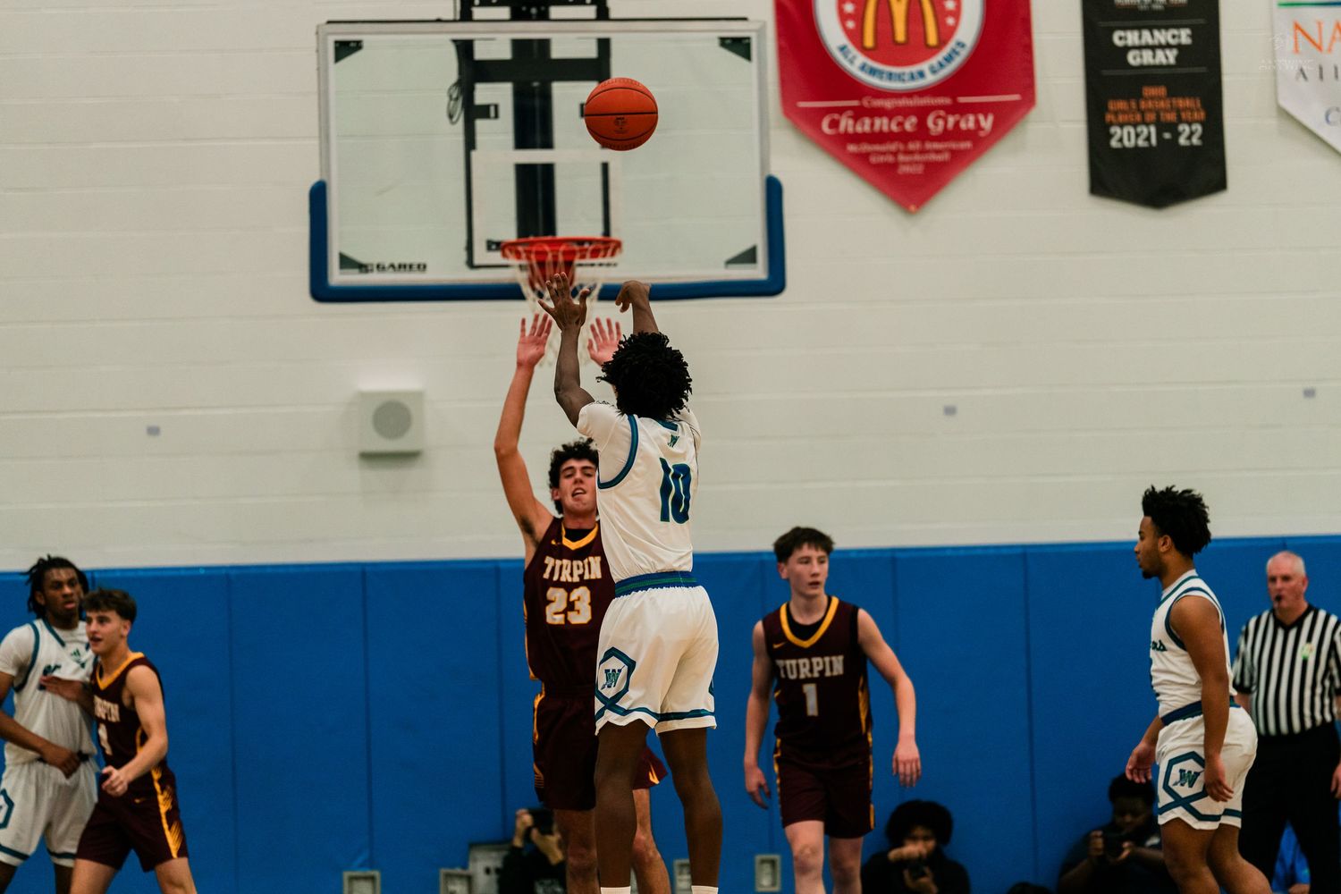 Winton Woods player #10 shoots over Turpin defenders during high school basketball game near the basket.