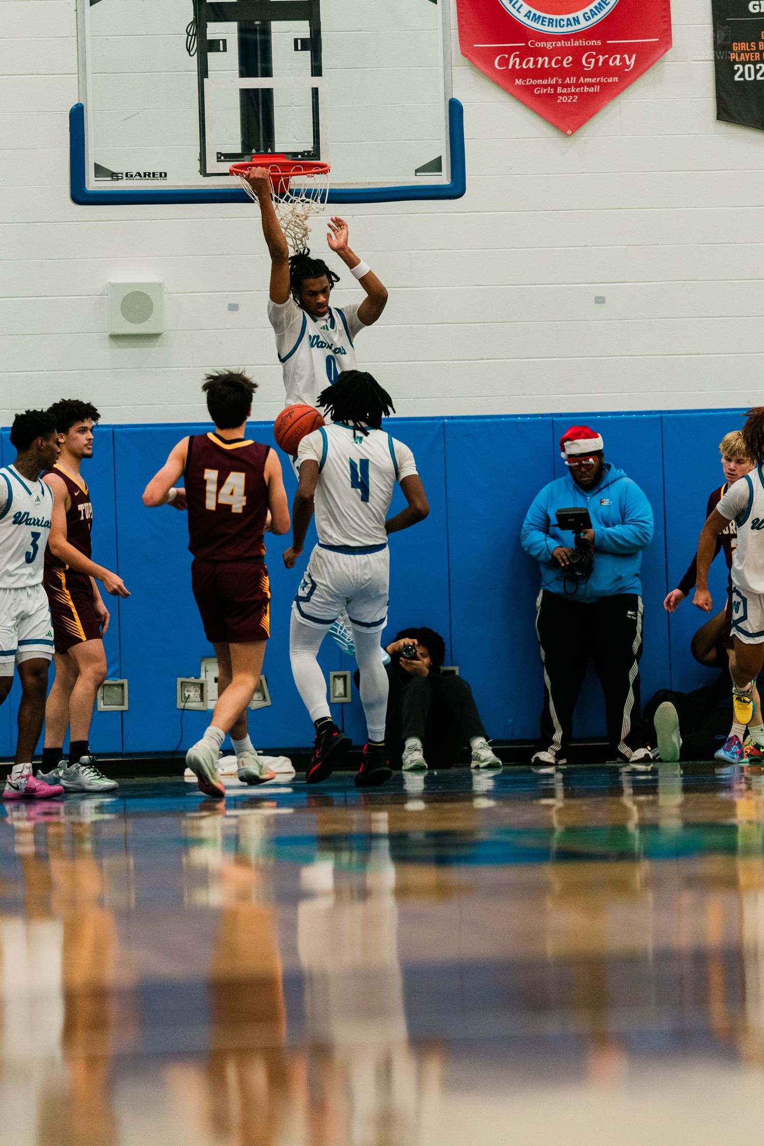 Home team player dunks basketball while Turpin players in maroon uniforms watch during competitive high school game.