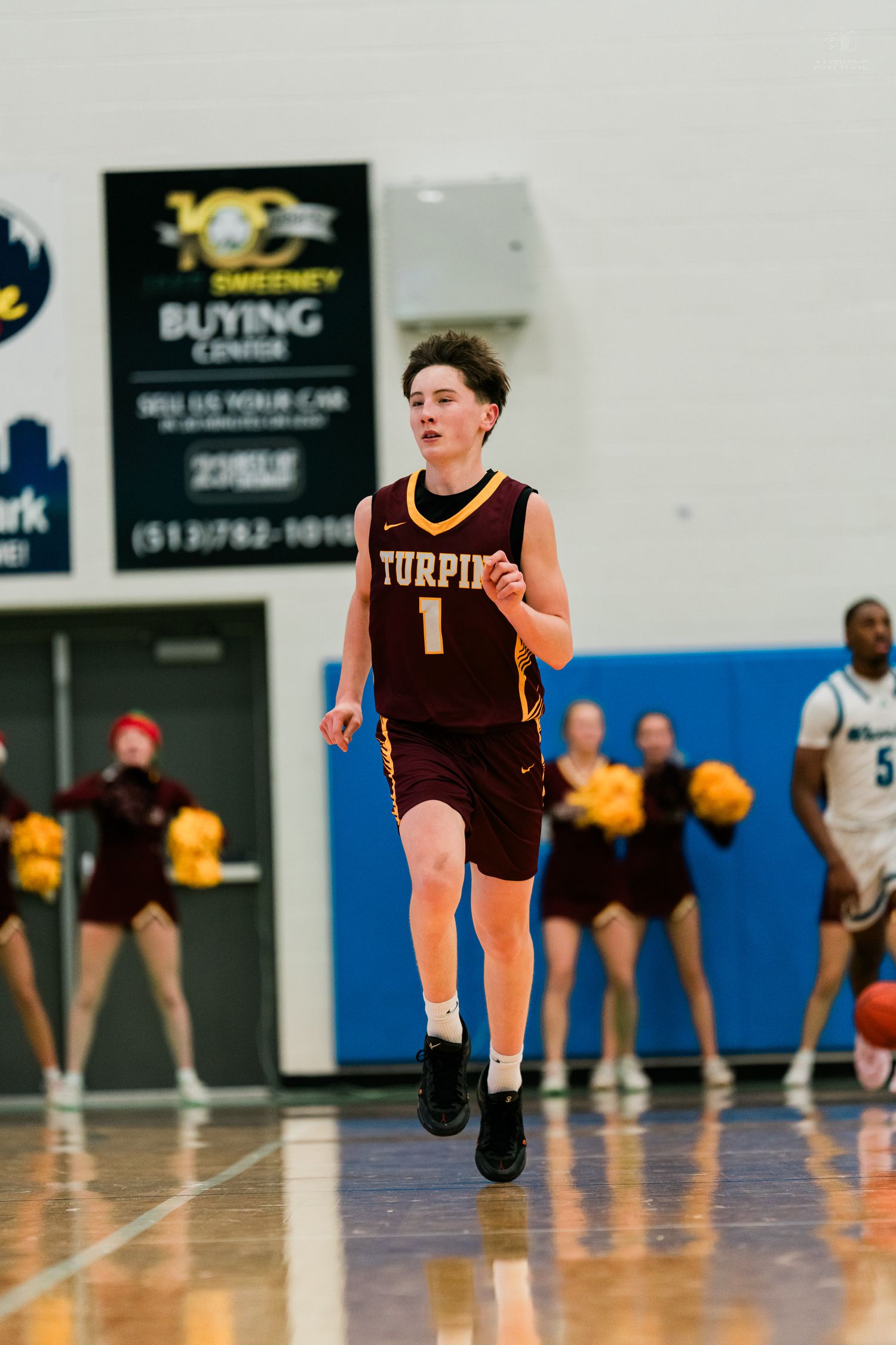 Turpin High School basketball player number 1 in maroon Nike jersey runs down the court during a game.
