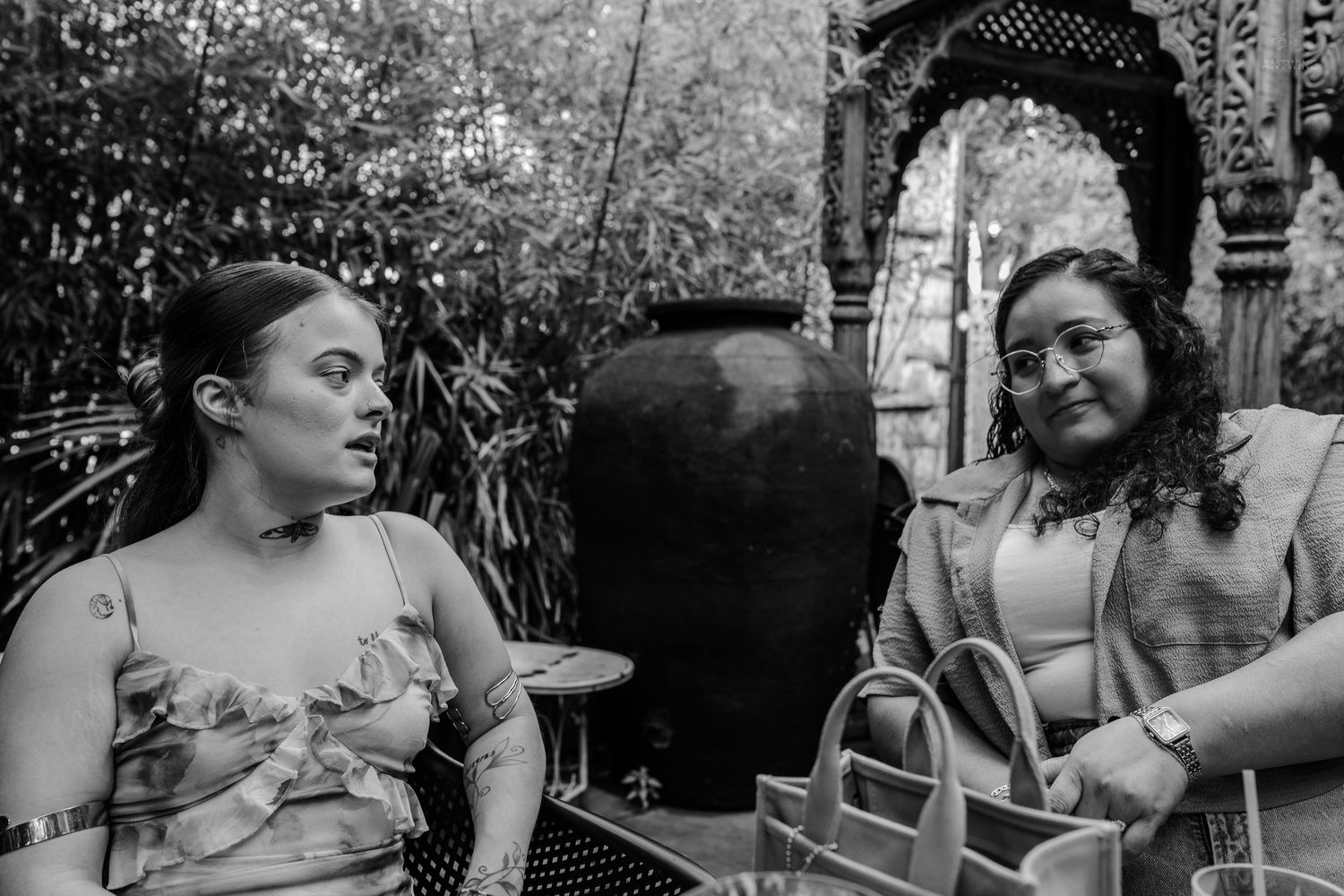Black and white photo of two women in conversation at an outdoor venue with decorative architecture.
