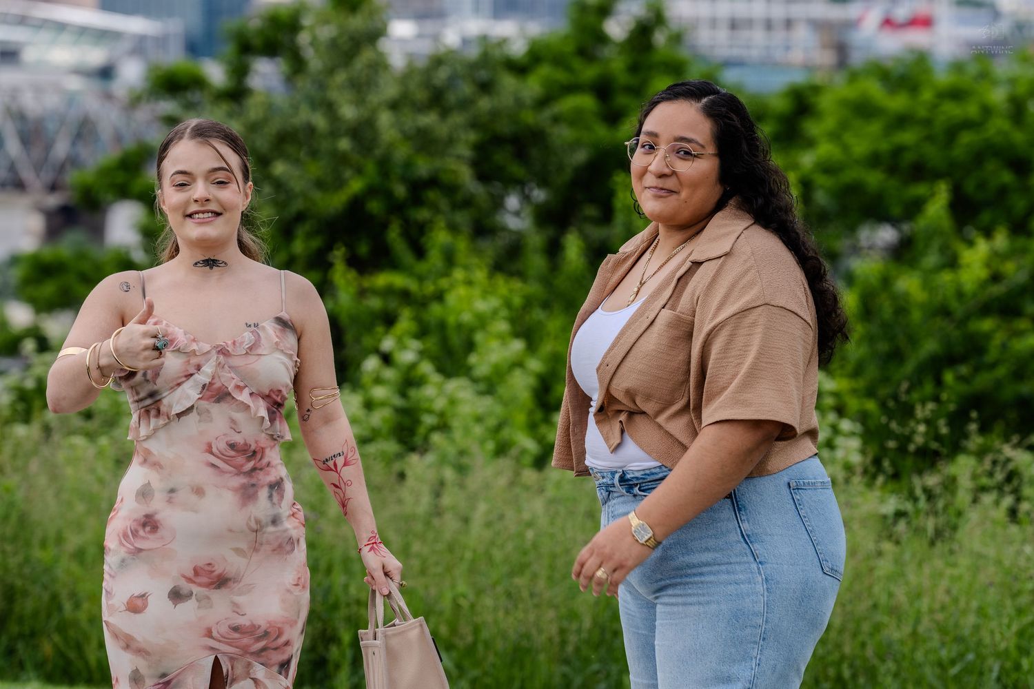 Two smiling women posing together in a lush green outdoor park setting.