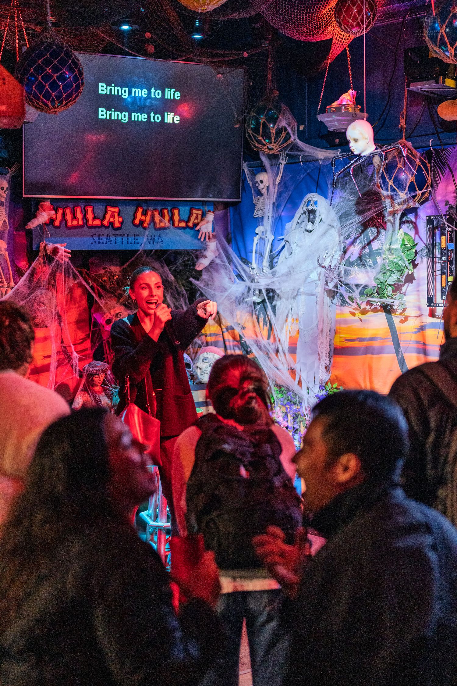 Singer performing Bring Me to Life karaoke at Halloween-decorated Hula Hula bar Seattle.