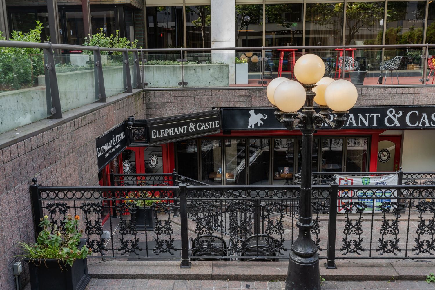 Elephant and Castle pub entrance with ornate black iron railings and globe lights in a city plaza.