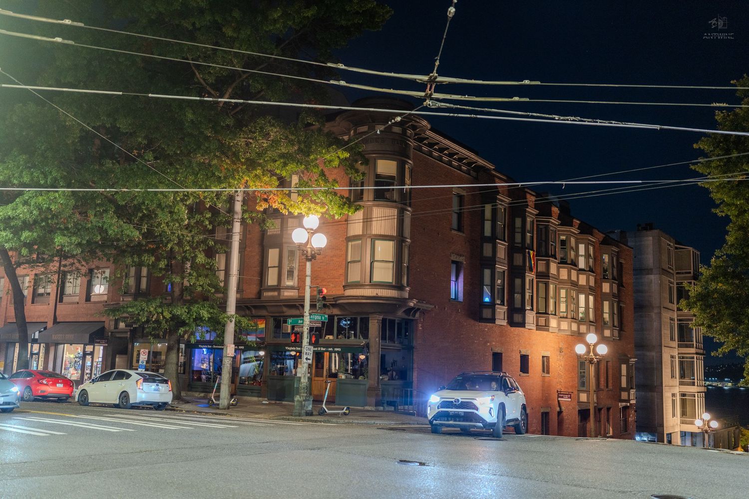 Historic red brick corner building illuminated at night with street lights in urban Seattle.