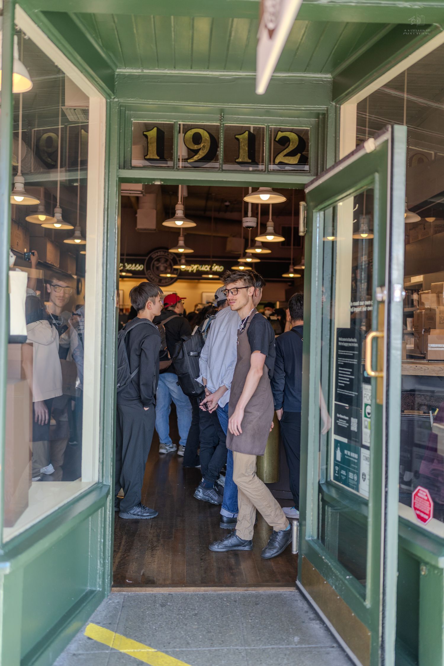 Customers entering a historic 1912 market shop with green wooden door frame.