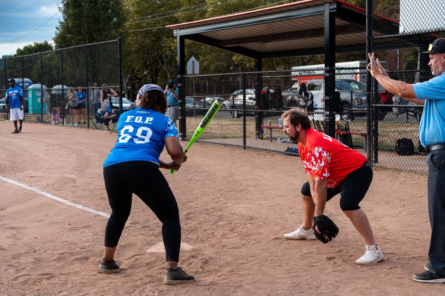 A softball batter in a blue FGP 89 jersey prepares to swing while a catcher crouches behind home plate.