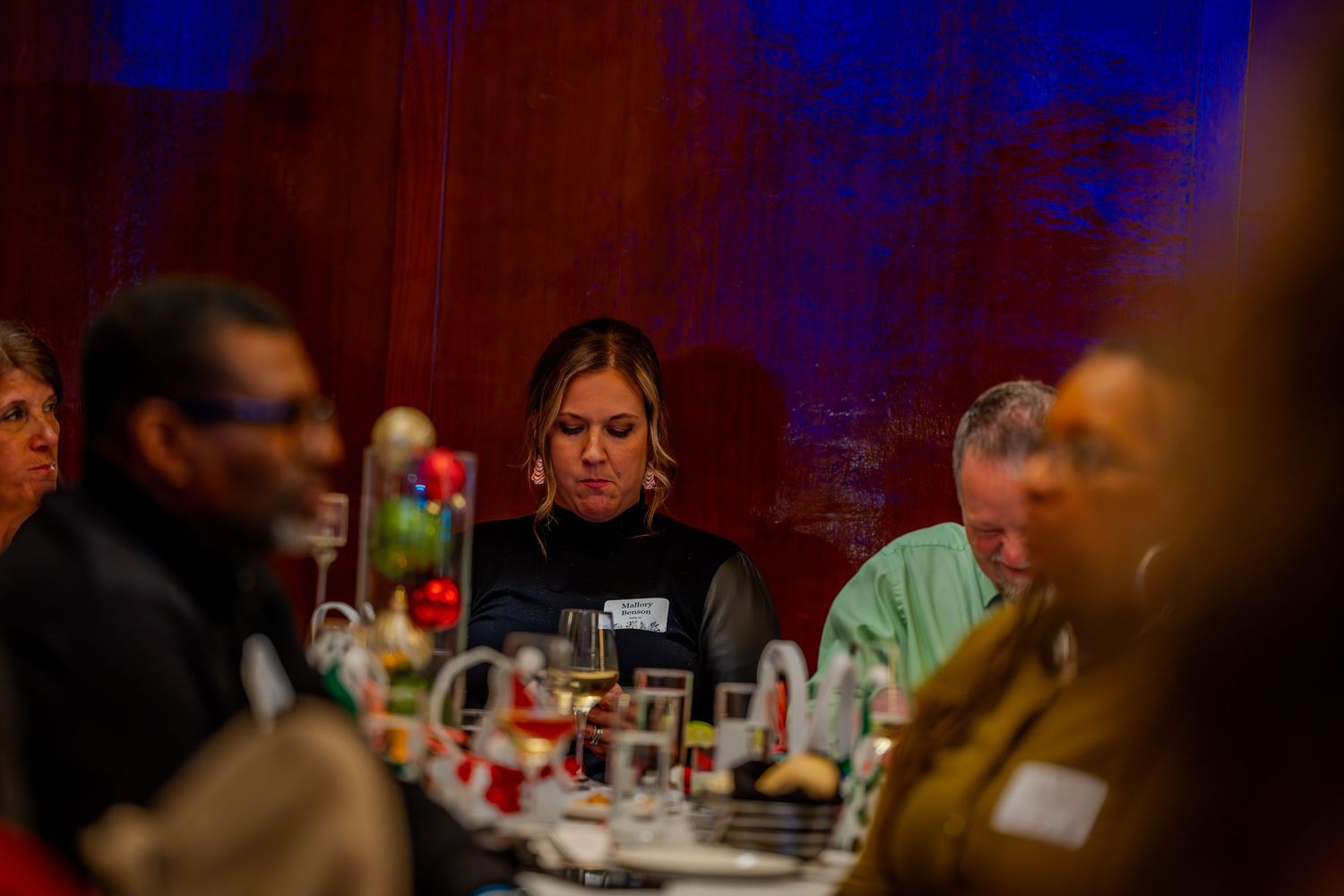 People seated at a decorated banquet table during a formal dinner event in a dimly lit venue.