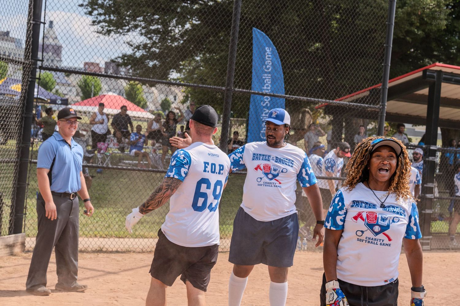 Softball players in Battle of the Badges jerseys celebrate on the field together.