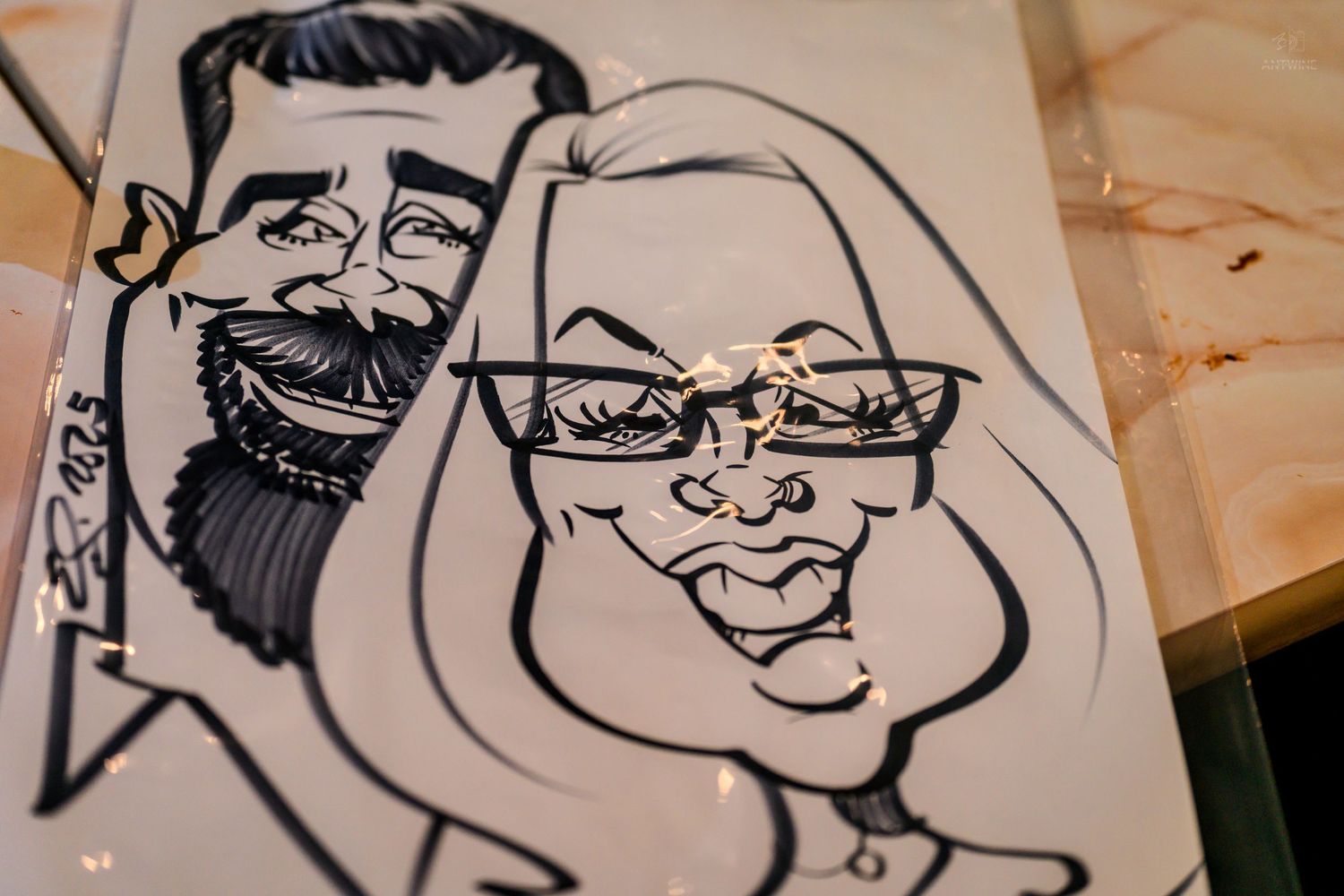 Hand-drawn caricature art of a bearded man and a woman wearing glasses as a couple.