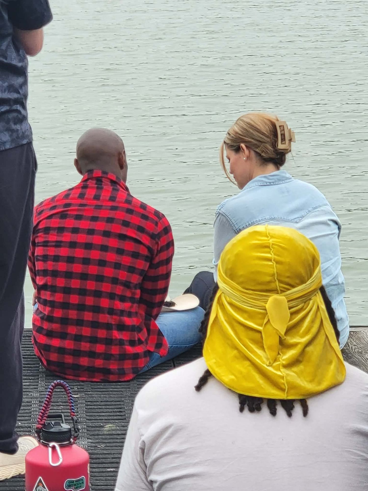 Two people sitting on dock overlooking calm water during film shoot.