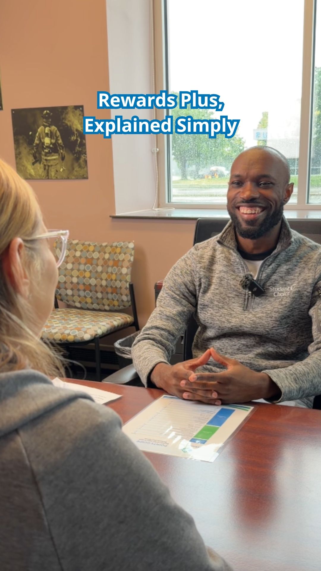 Two people sit across a desk smiling, with text overlay reading Rewards Plus, Explained Simply.