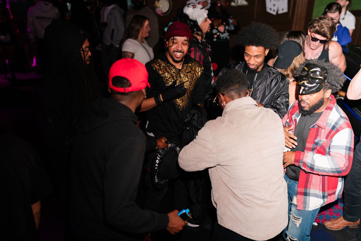 Diverse group of partygoers mingling at a festive Halloween nightclub event.