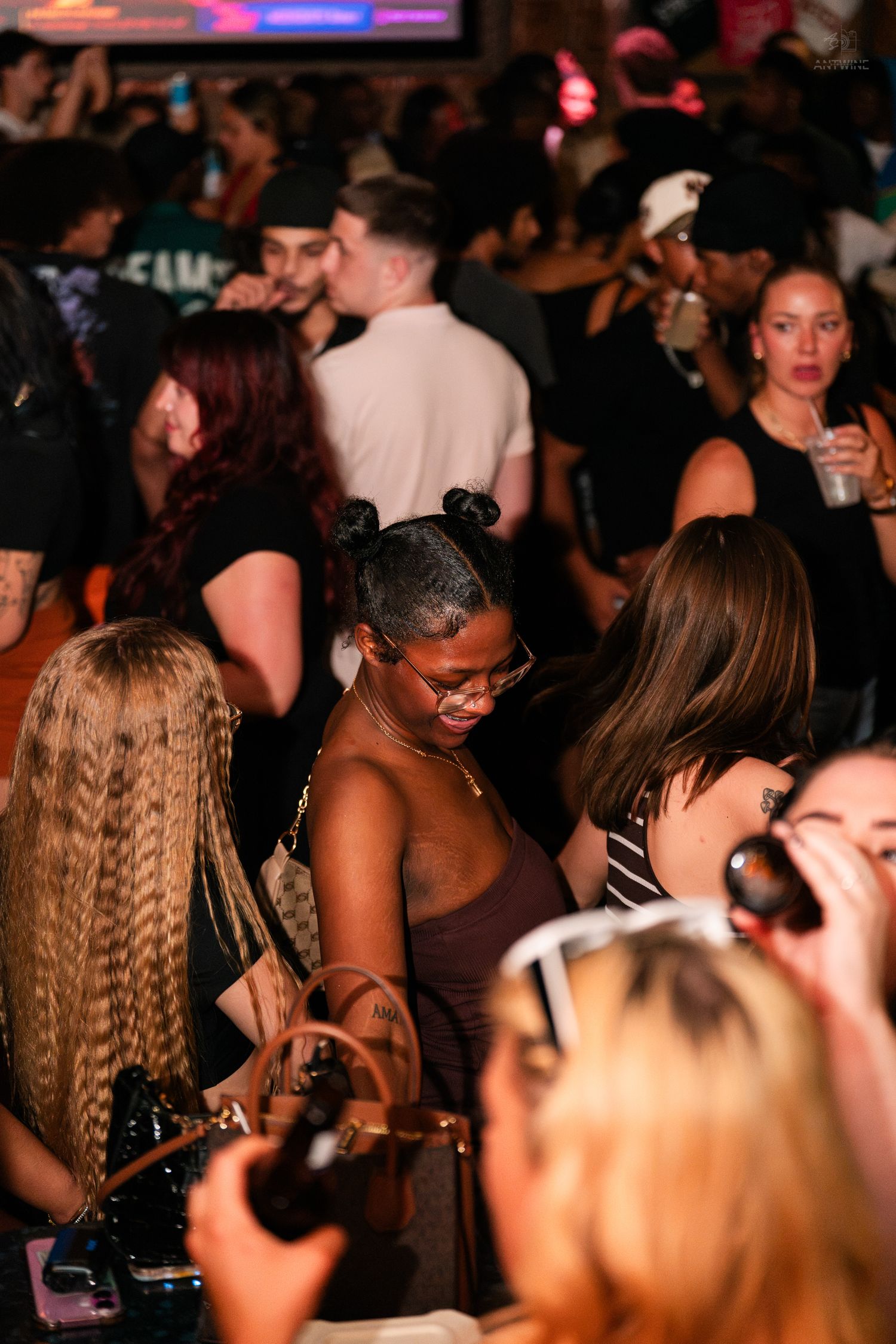 Diverse crowd of people dancing and socializing at a busy nightclub.