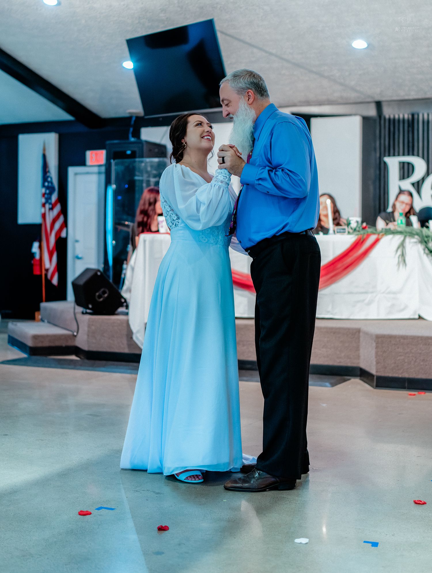 Bride in light blue gown shares emotional father-daughter dance at wedding reception.