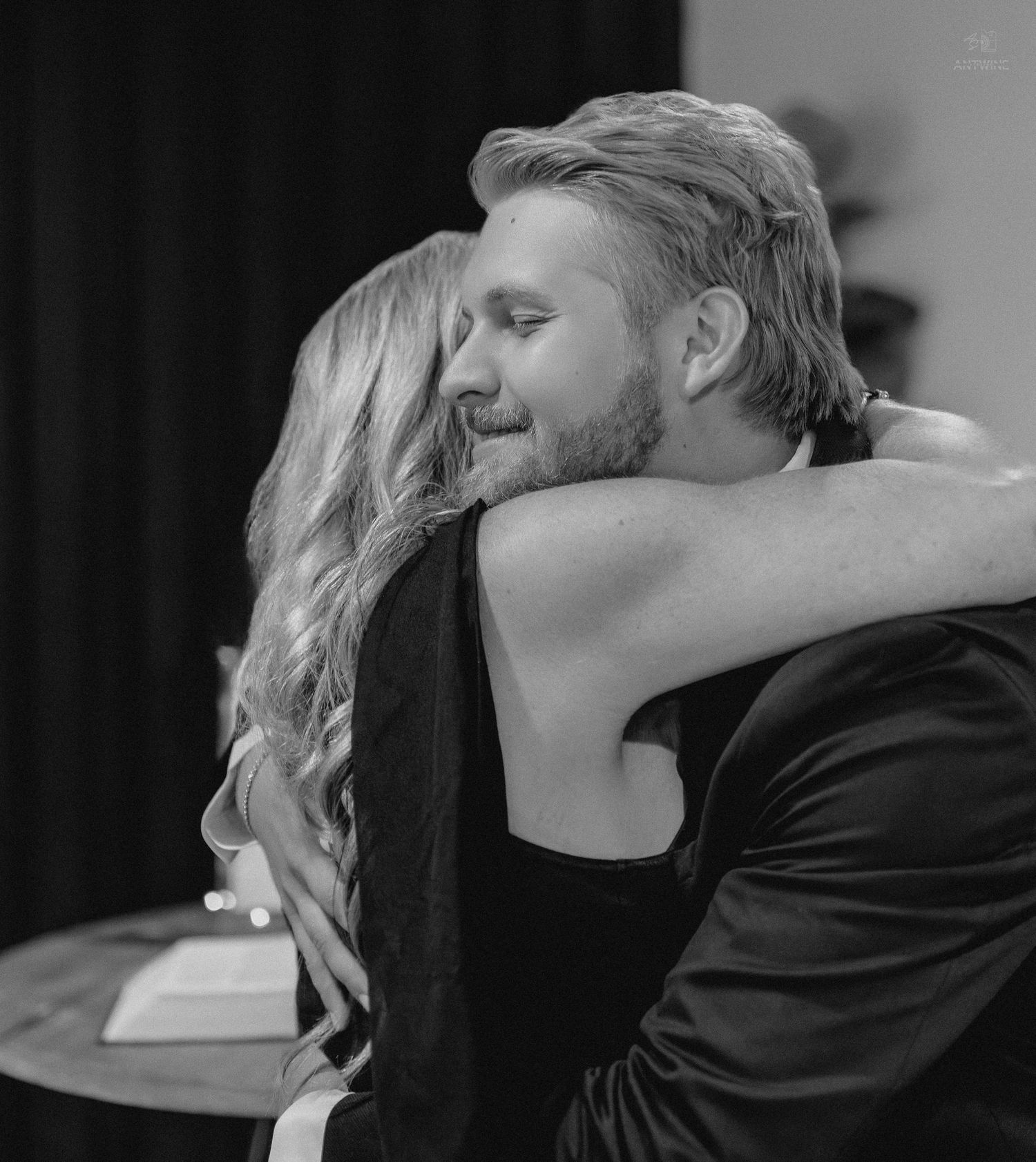 Couple shares a warm embrace in an intimate black and white wedding reception photo.
