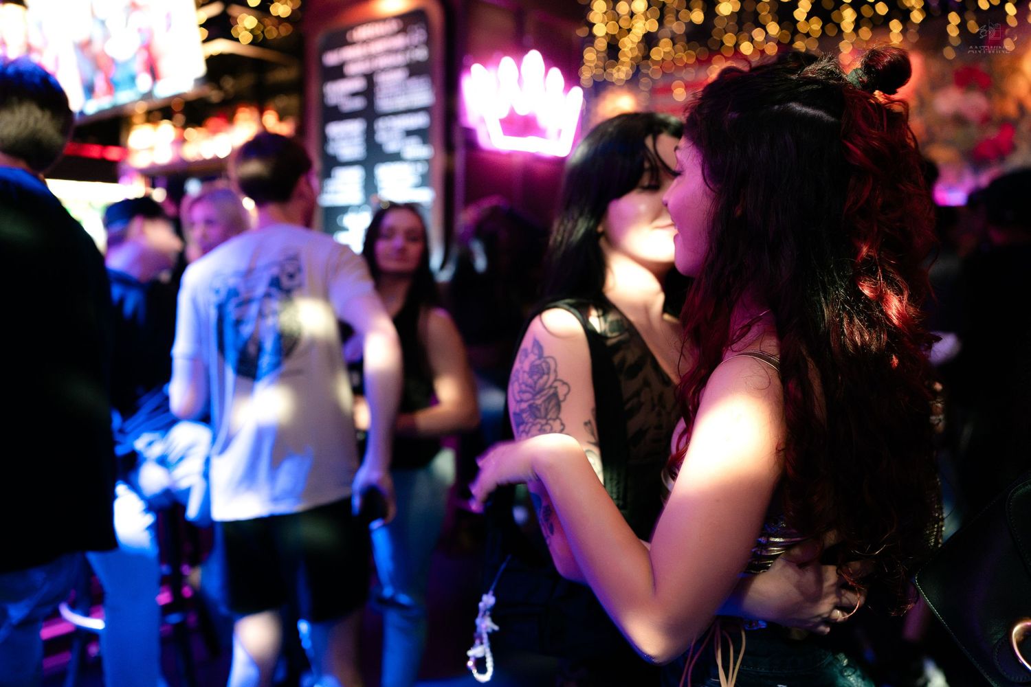 Tattooed woman with long dark hair enjoying a lively nightclub event.