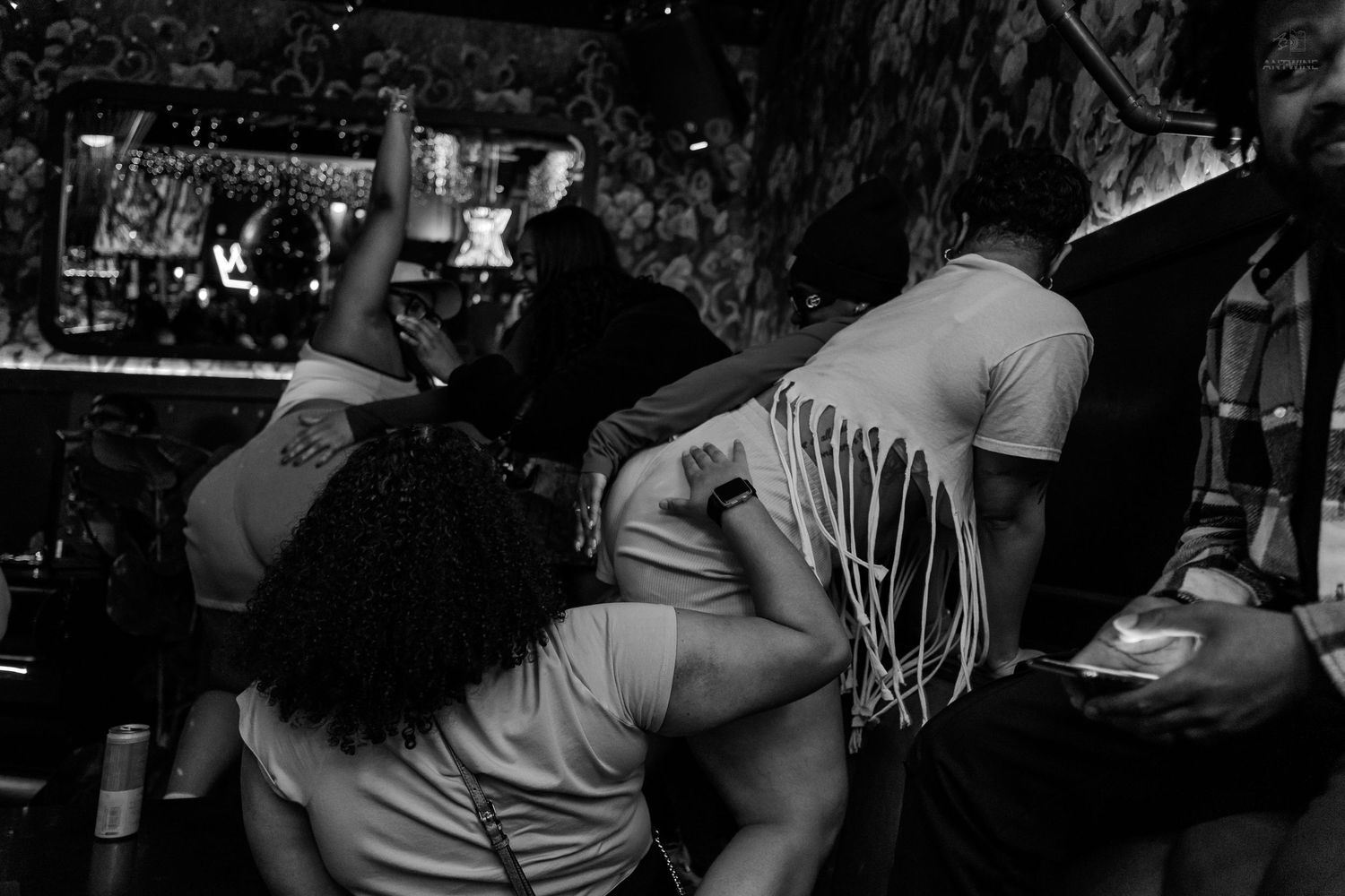 Black and white photo of people dancing closely together at a lively nightclub party.