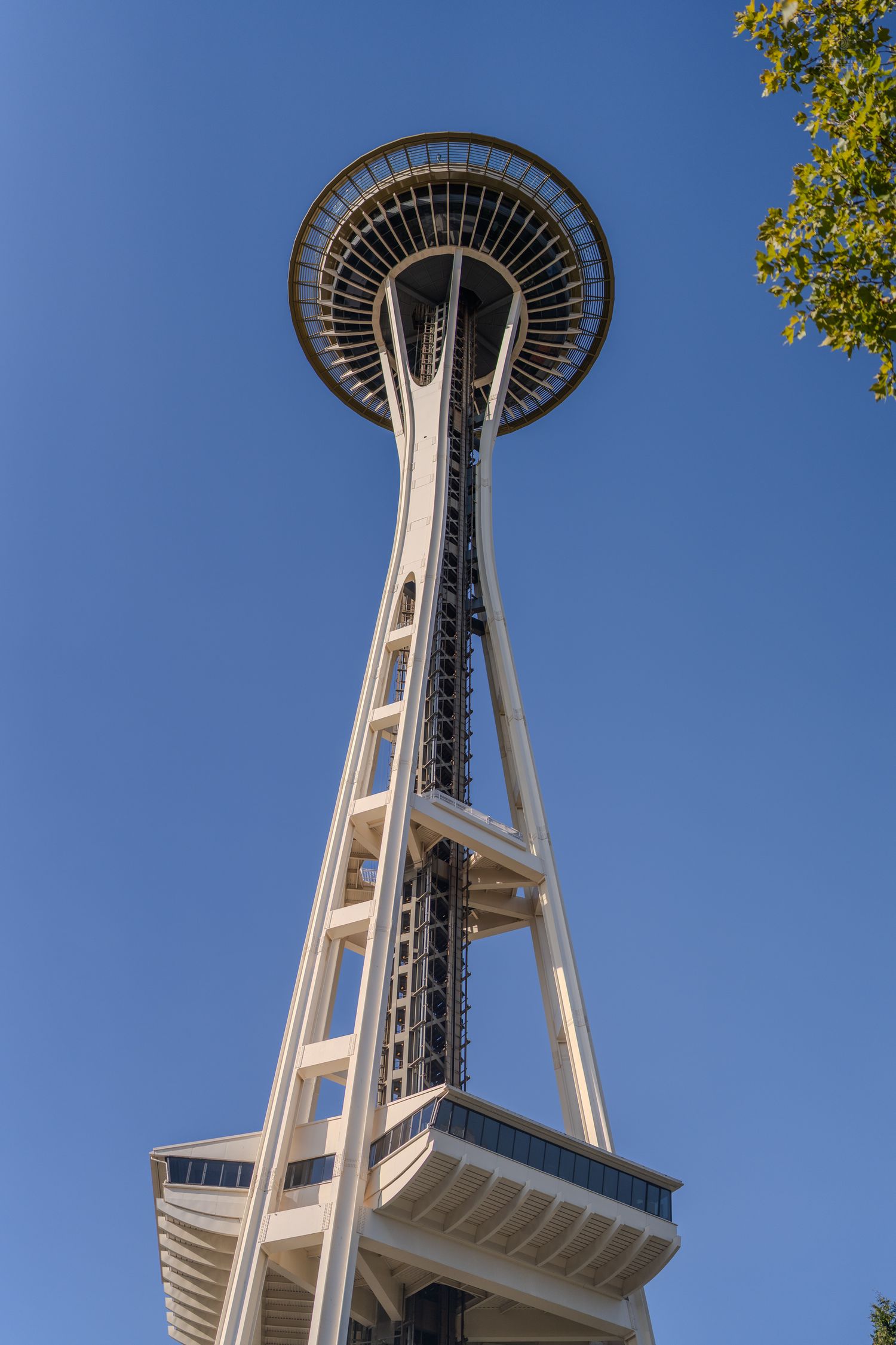 Low angle view looking up at the iconic Seattle Space Needle against a clear blue sky.