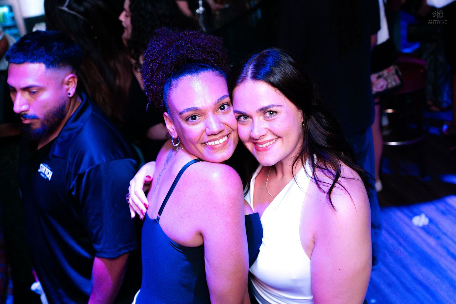 Two smiling women posing together at a fun nightclub event.