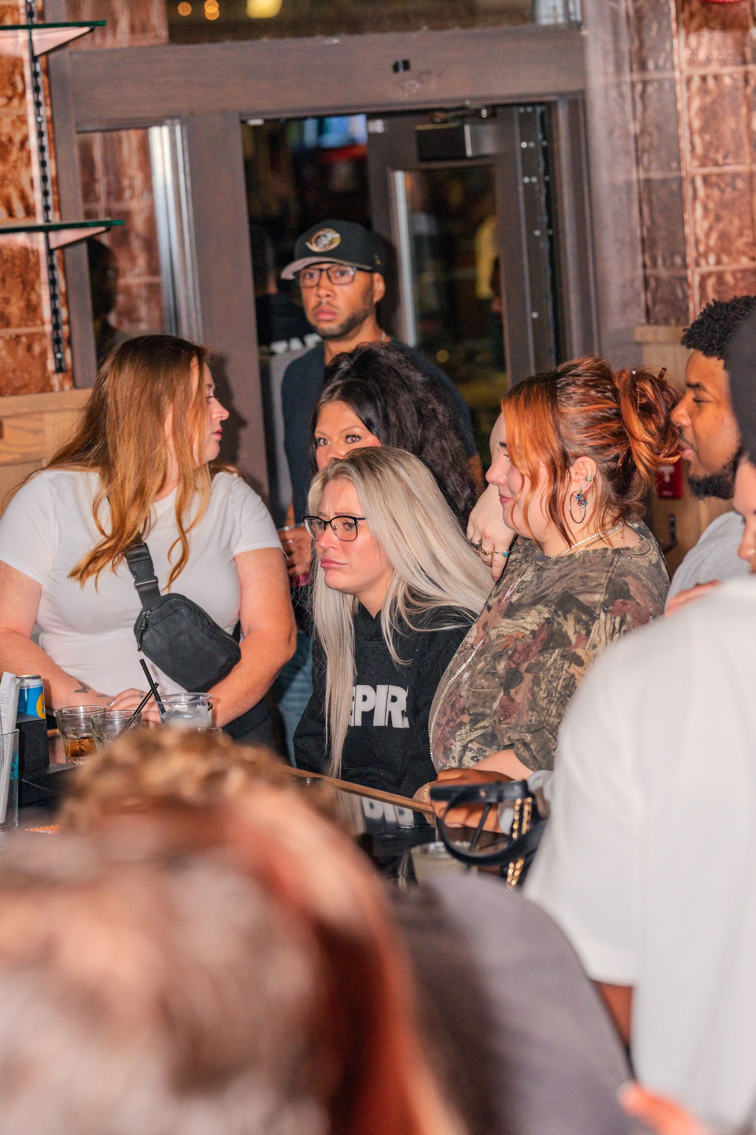 Group of women gathered at a busy bar counter during a crowded nightlife event.