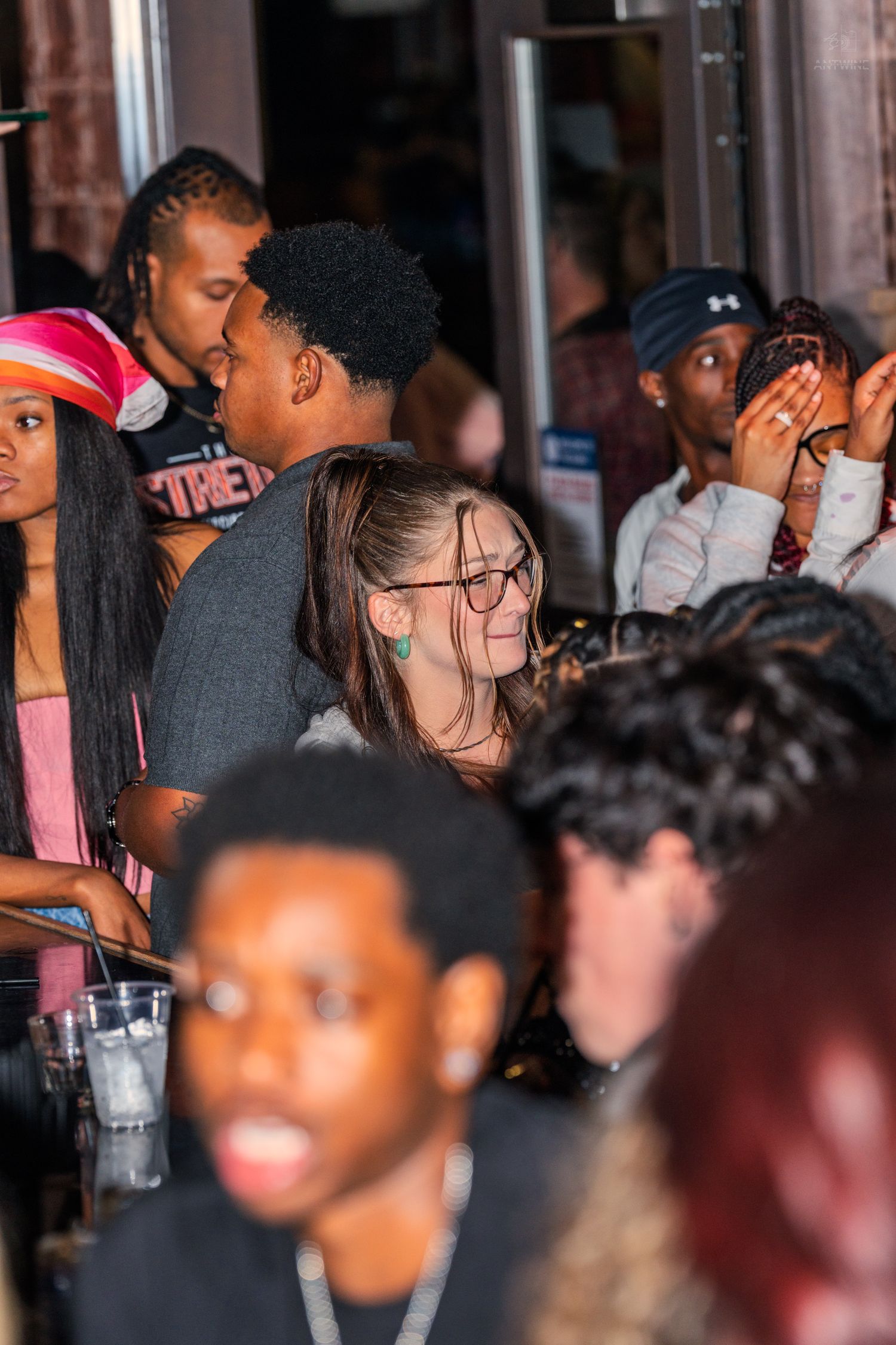Diverse group of young people socializing and laughing together at a crowded indoor event.