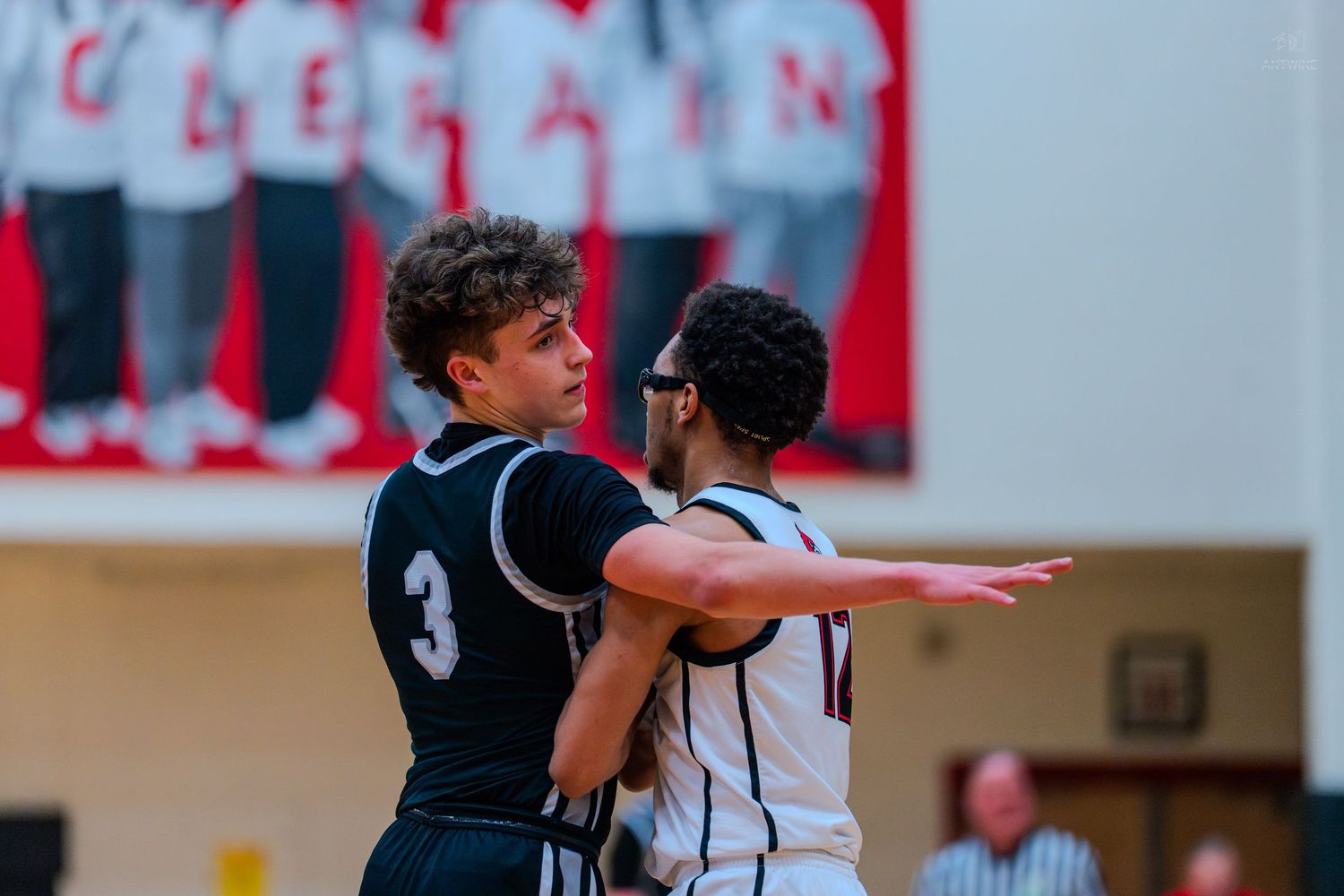 Two high school basketball players jostle for position near the baseline during a competitive game.