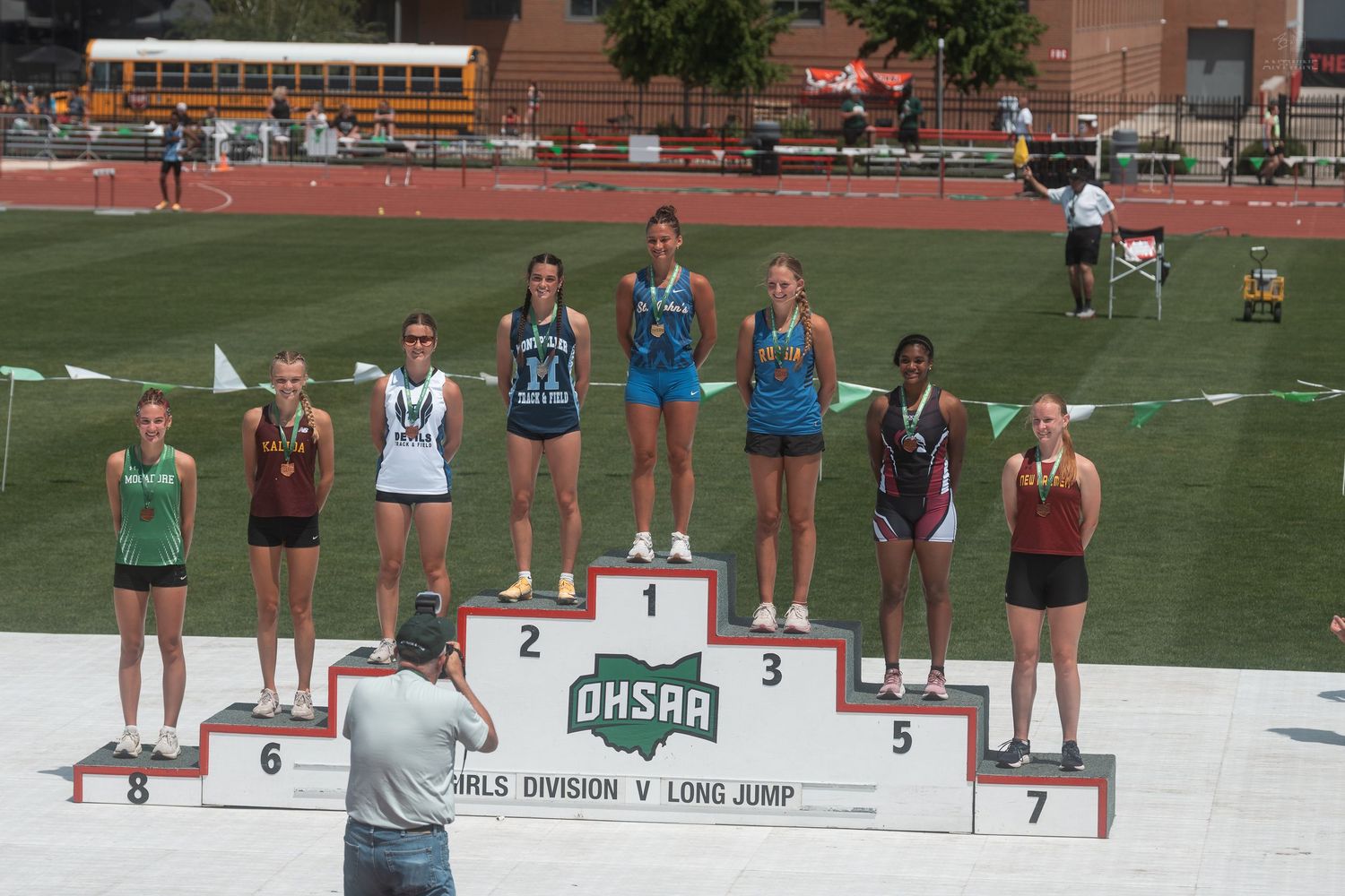 Girls Division V Long Jump finalists pose on OHSAA state championship awards podium outdoors.