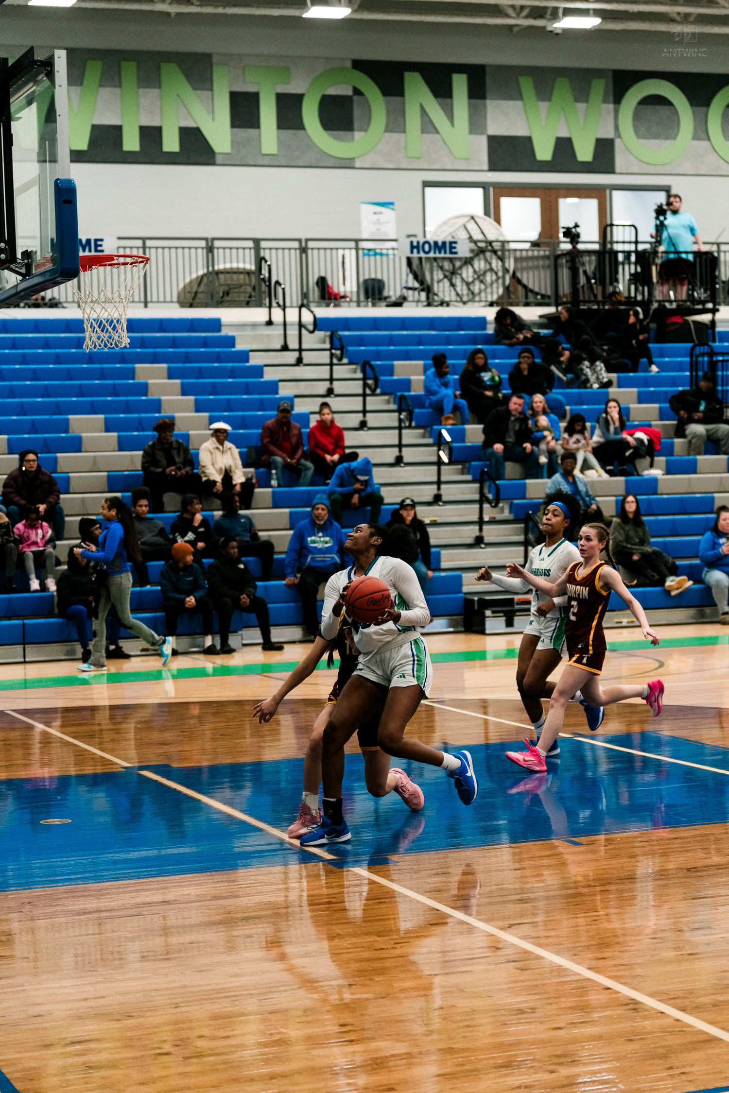 A Warriors girls basketball player drives to the basket past Turpin defenders in a high school game at Vinton Wood.
