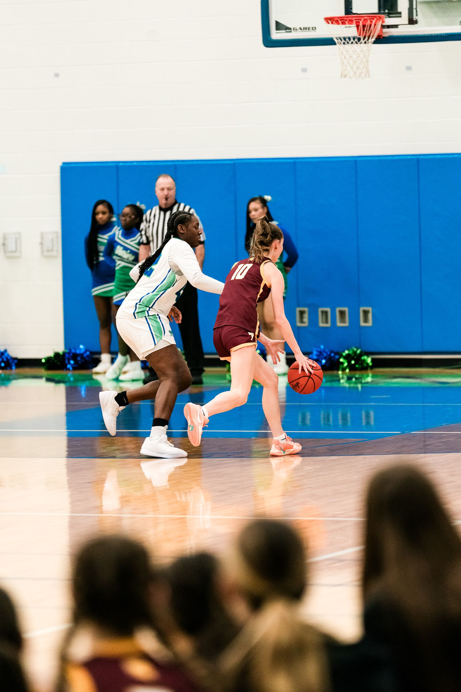 A Warriors player in green and white defends against a Turpin player dribbling the ball during a girls basketball game.