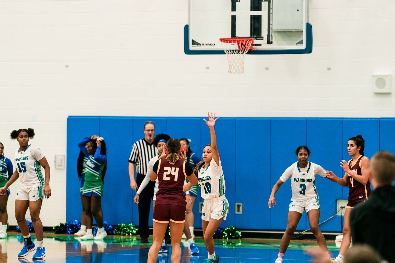 Warriors girls basketball player raises hand near hoop during high school game against Turpin team.
