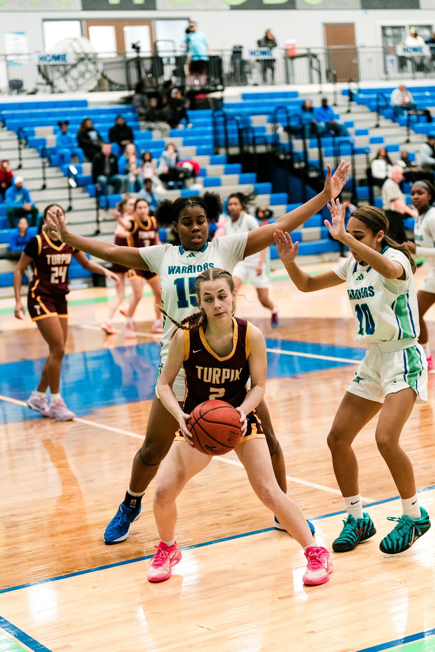 Turpin #2 holds the ball under pressure from Warriors #15 and #10 in a girls high school basketball game.
