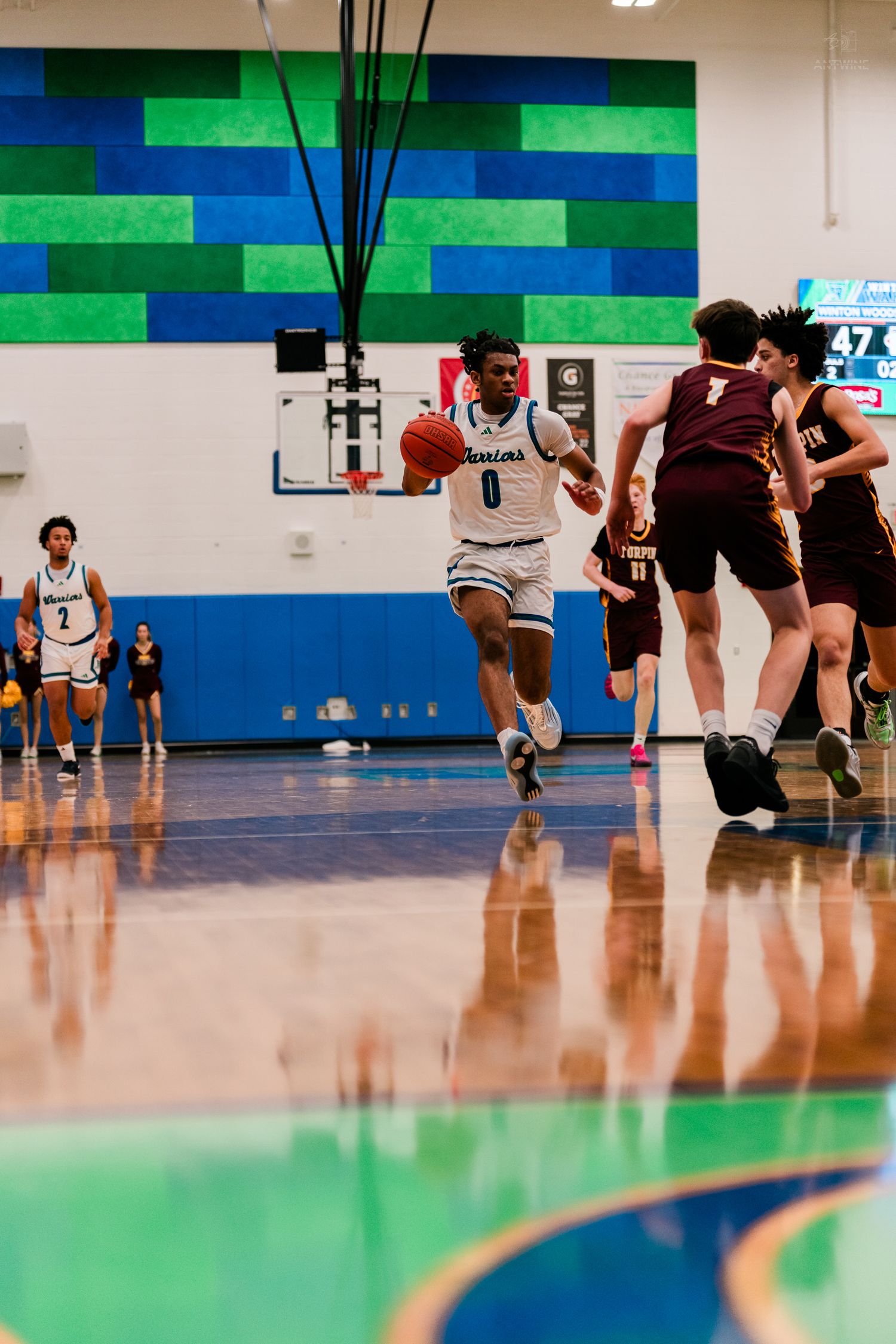 Warriors player number 0 drives toward the basket against Turpin defenders during a high school basketball game.