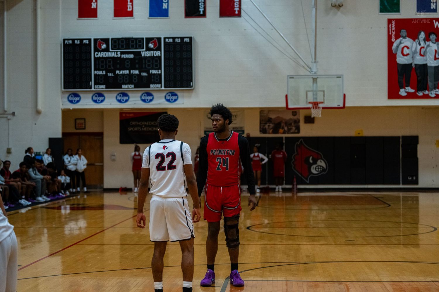 Two high school basketball players stand at the free throw line during a basketball game.